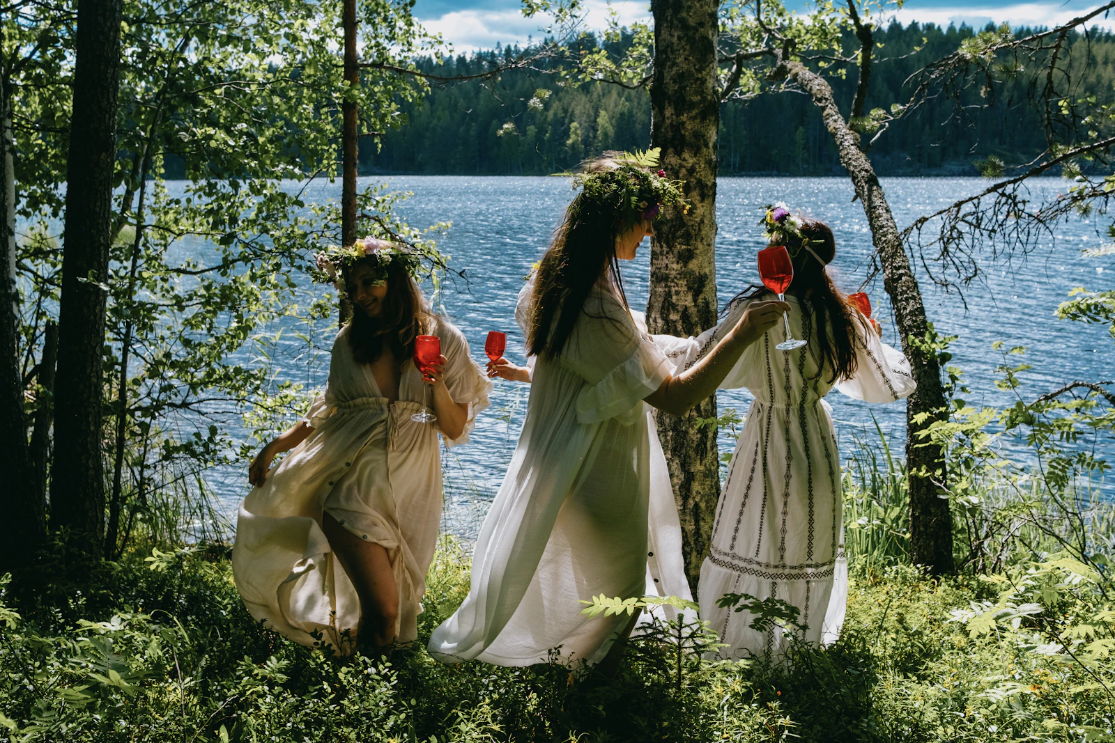 Summer visitors gather beside a forest-framed Finnish lake