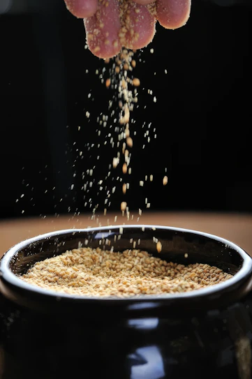 A person is sprinkling grain into a bowl