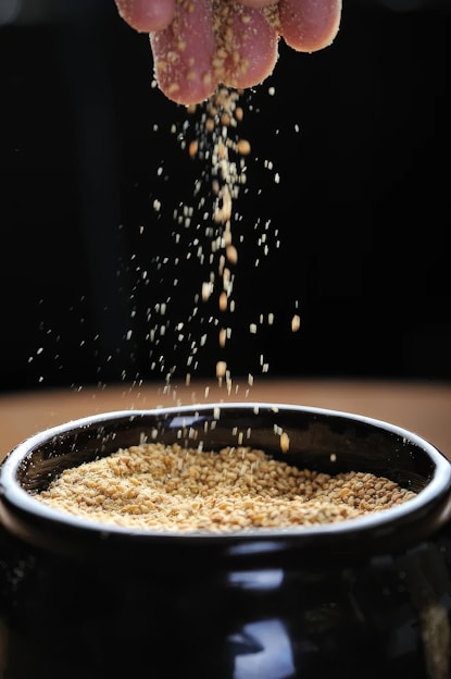 A person is sprinkling grain into a bowl