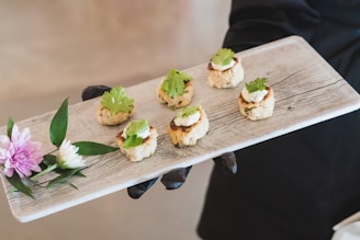 A person holding a tray with small appetizers on it
