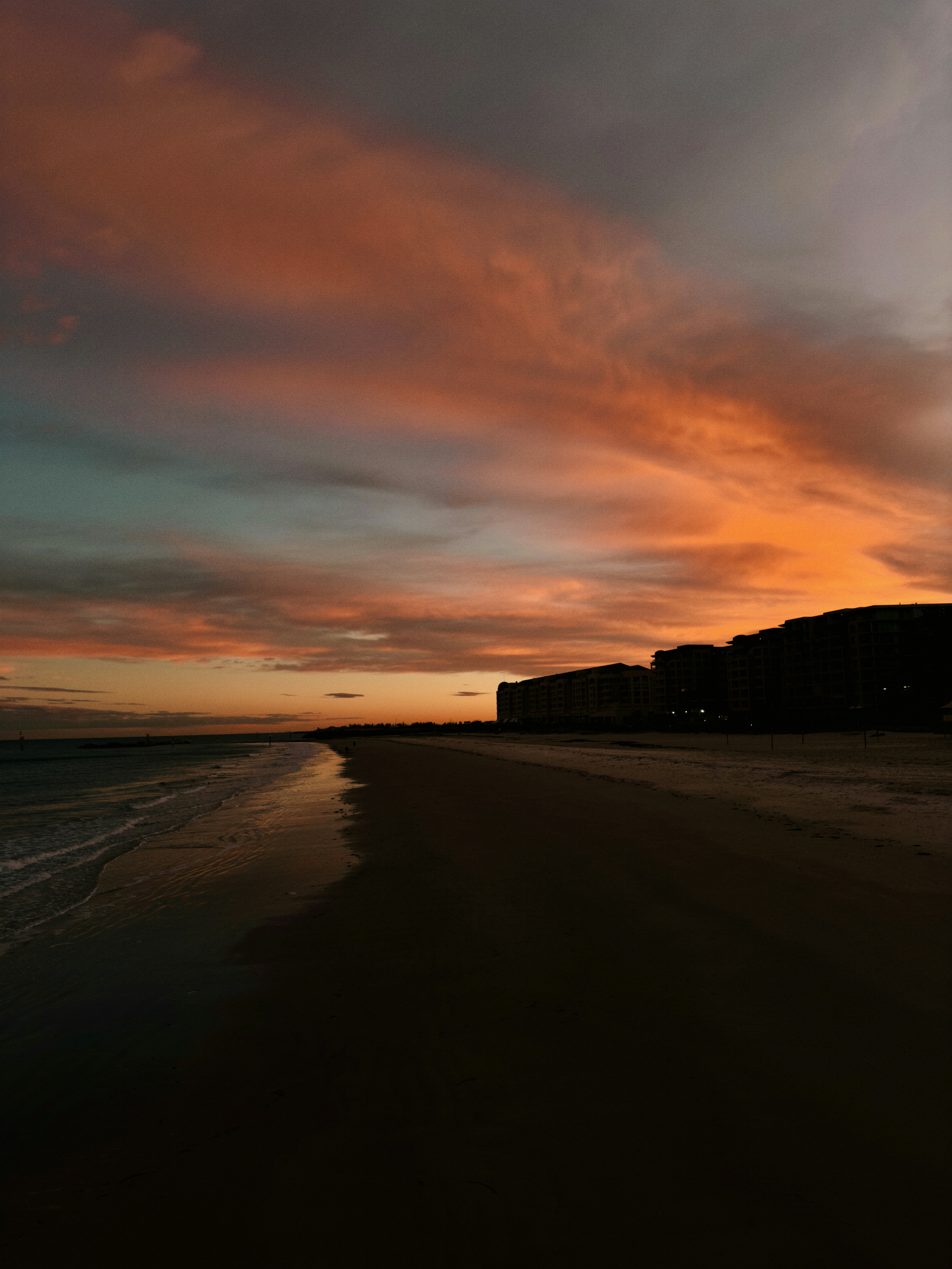 A sunset on a beach with a building in the background