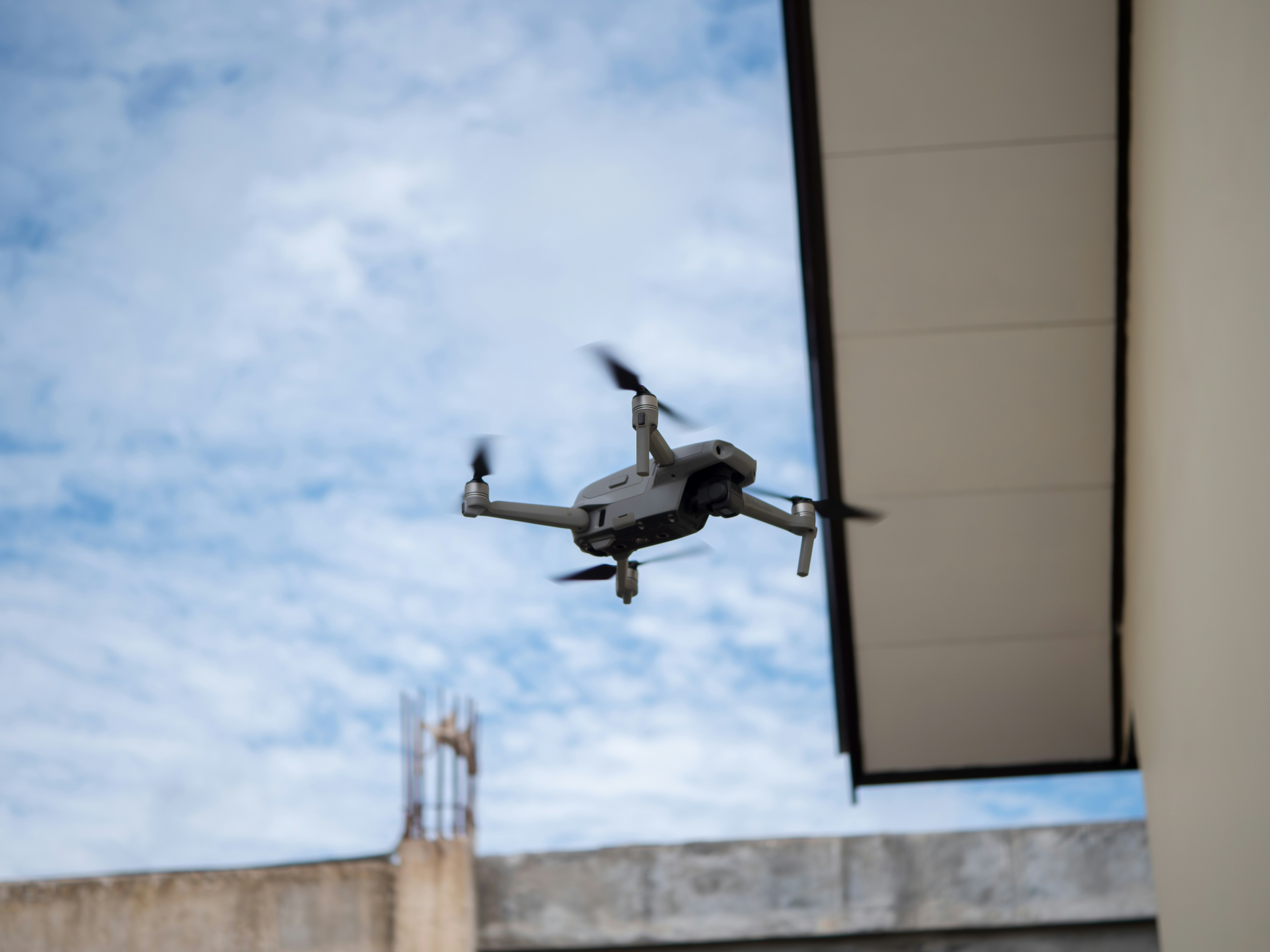 A small plane flying over a building under a cloudy sky