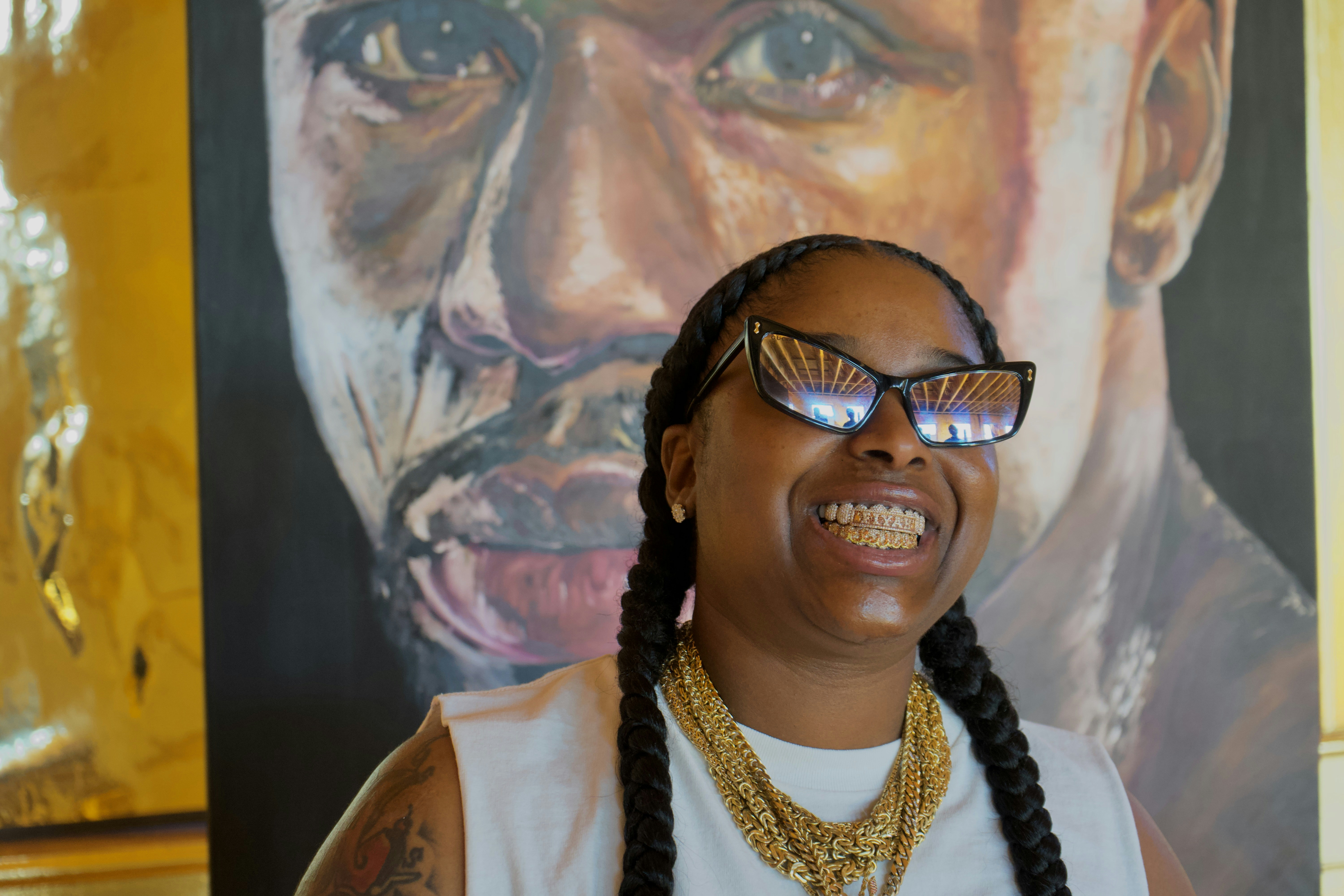 A woman with glasses and braids standing in front of a painting