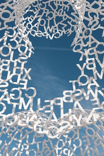 A sculpture made of letters is shown against a blue sky