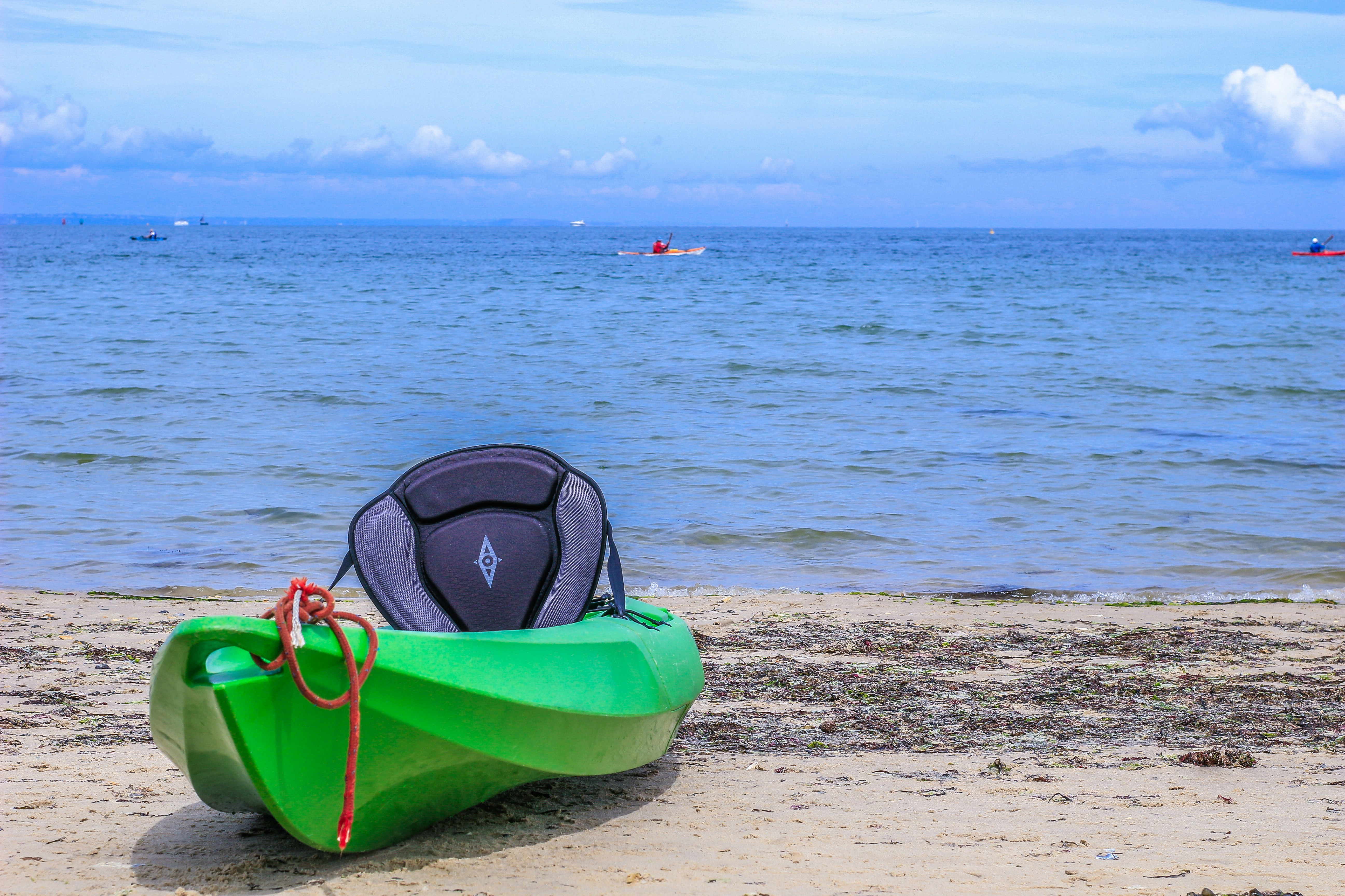 A green boat sitting on top of a sandy beach