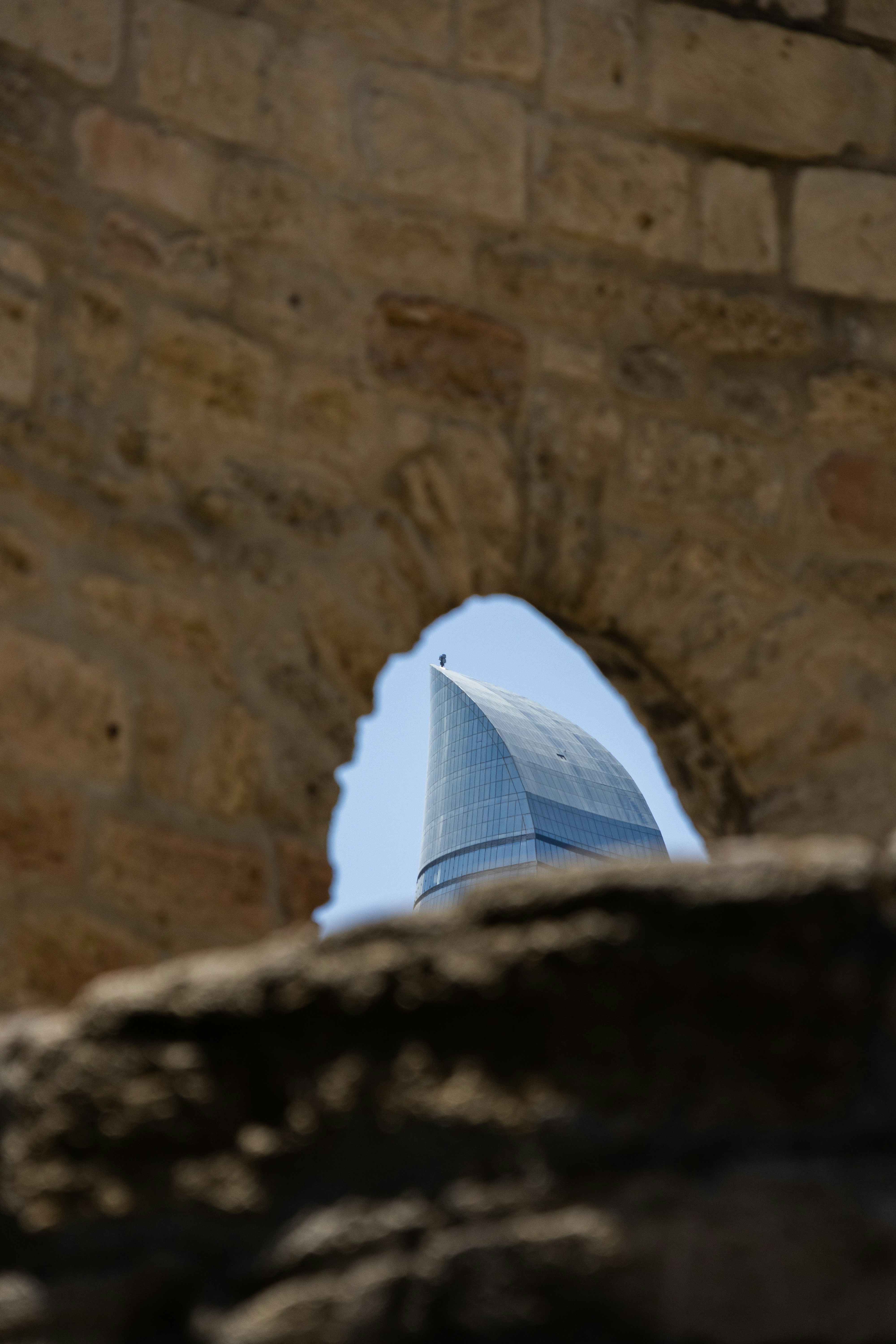 A view of a building through a hole in a stone wall