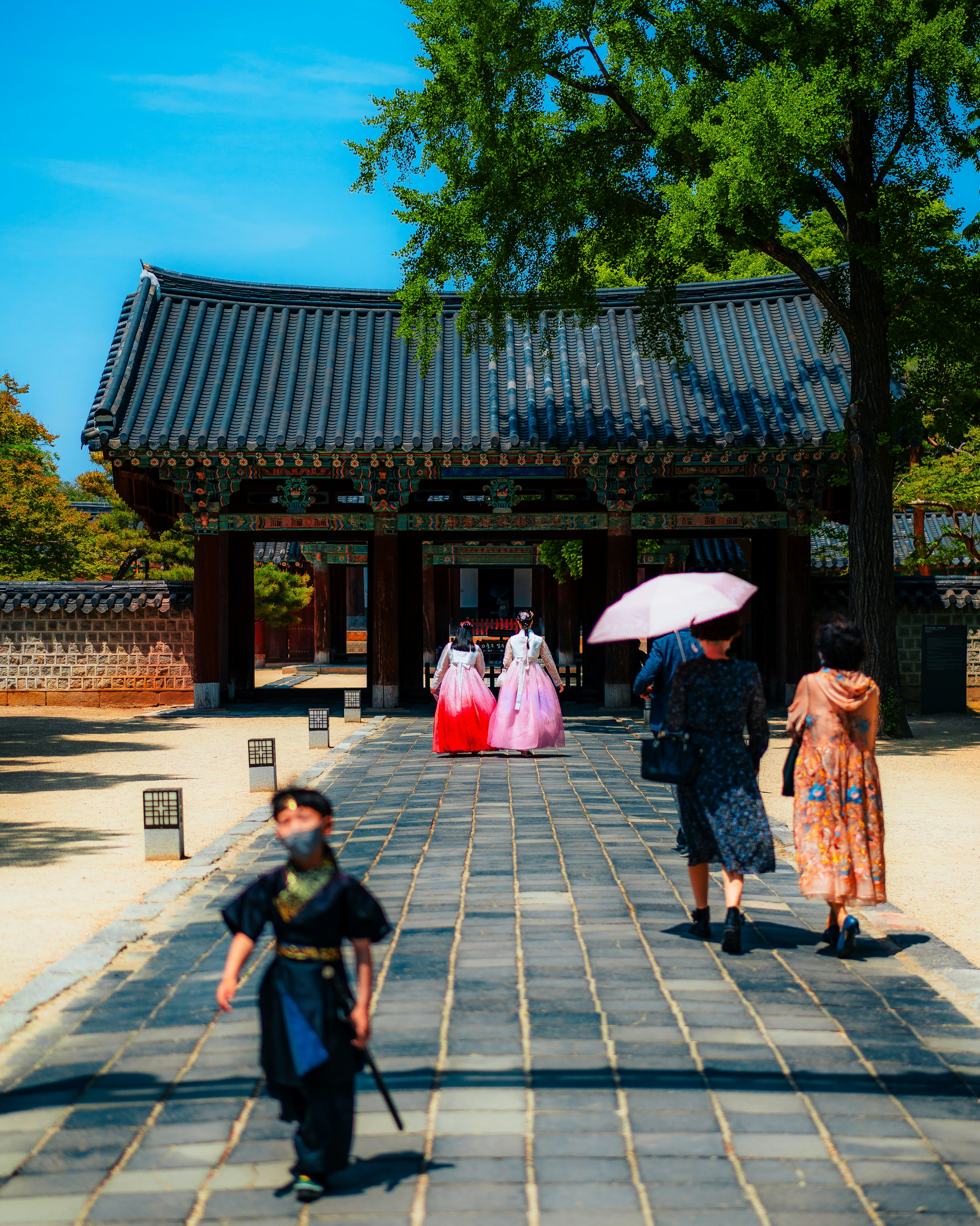 A group of people walking down a walkway with umbrellas