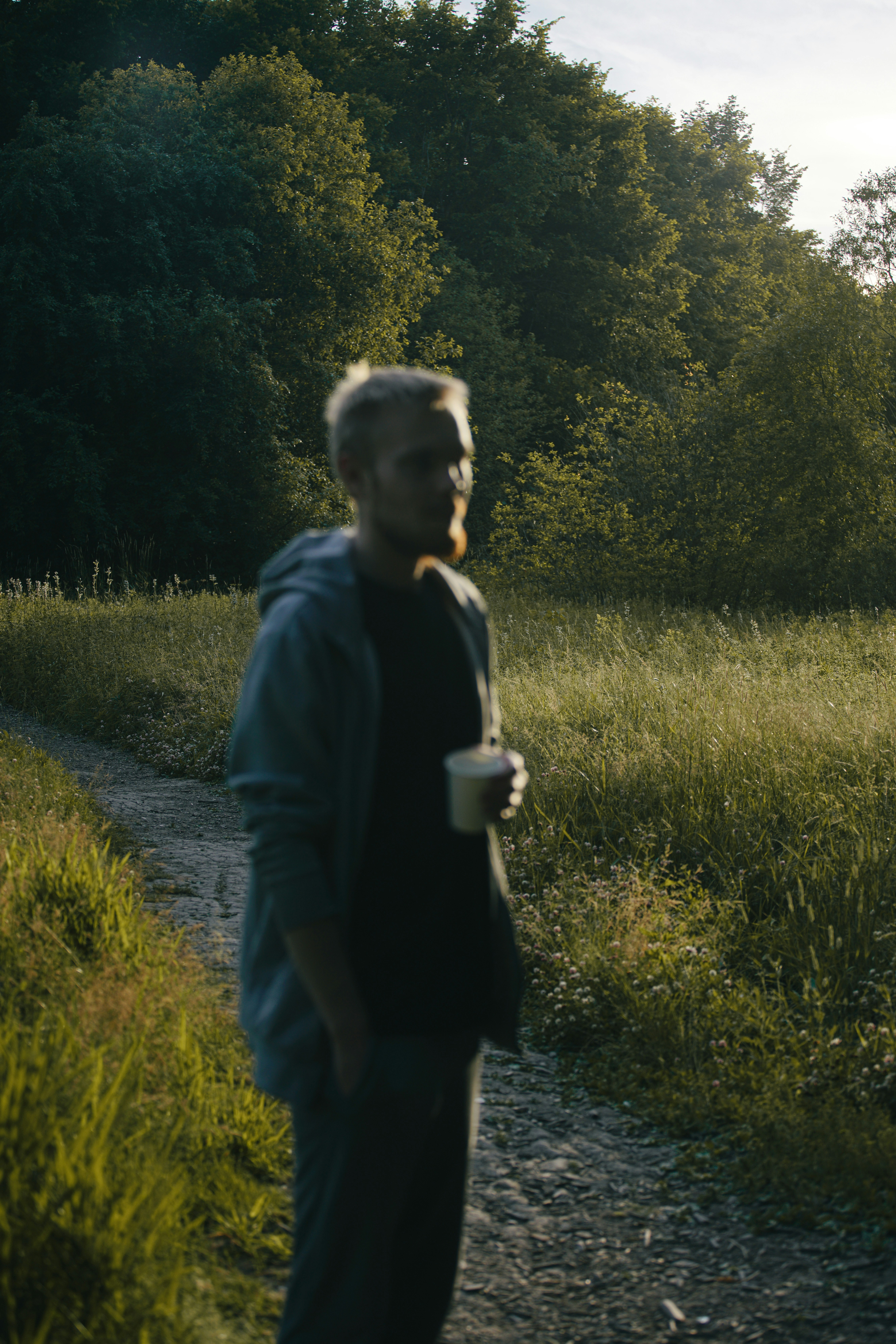 Un homme debout sur un chemin de terre à côté d’une forêt