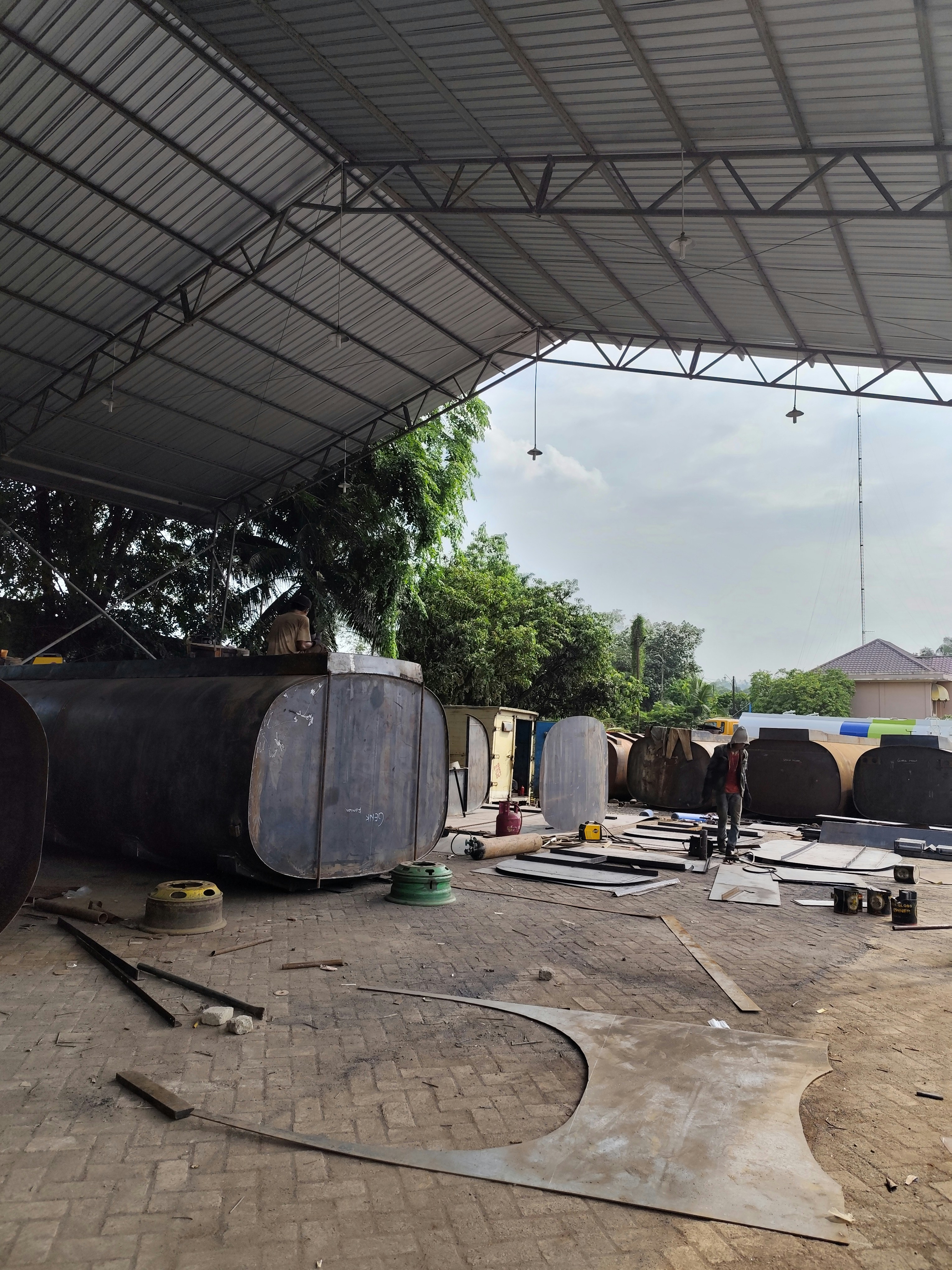 Construction workers installing large steel water tank panels on a South African farm site, bright open sky
