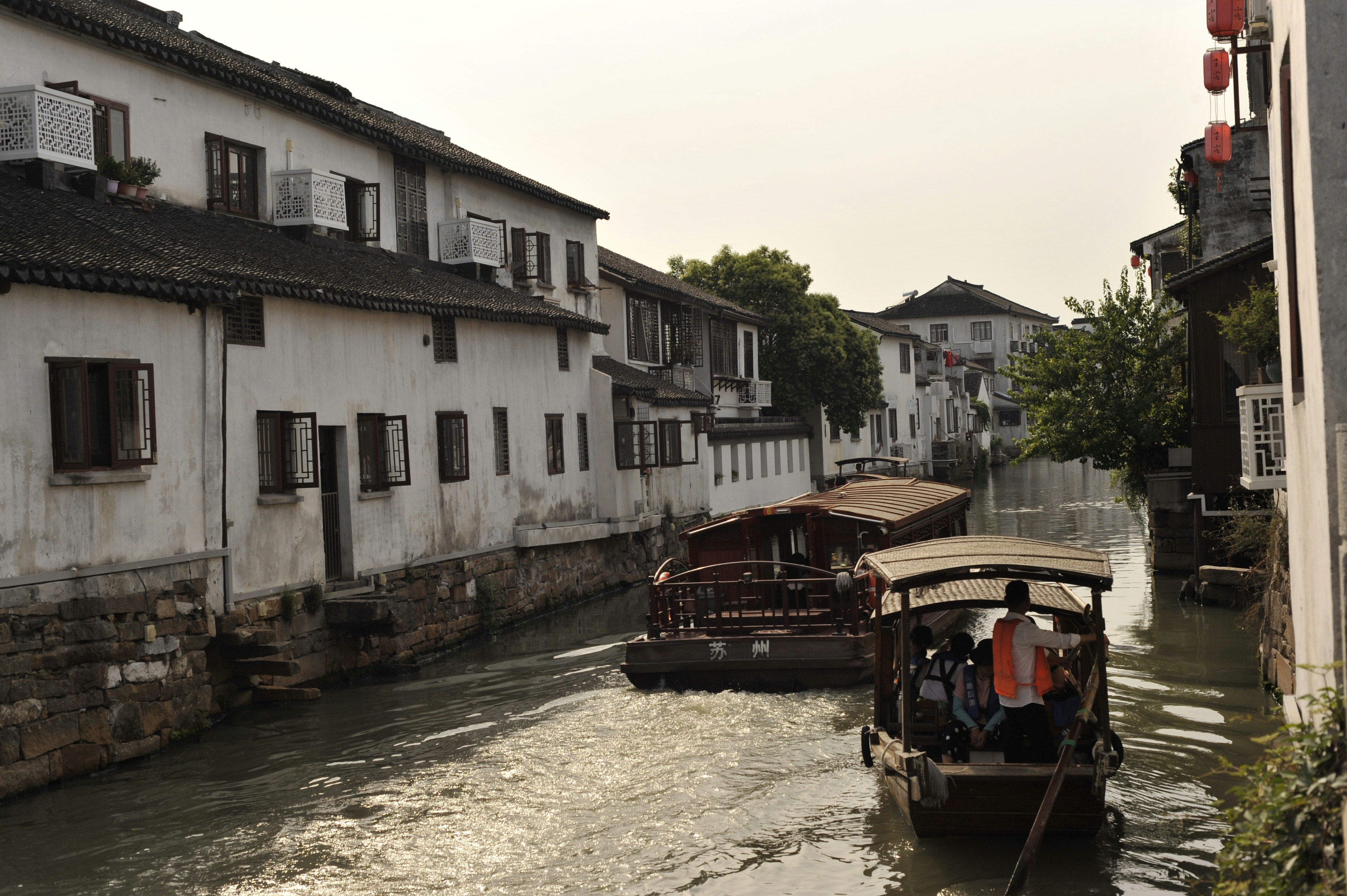 Eine Gruppe von Booten, die neben Gebäuden einen Fluss hinunterfahren