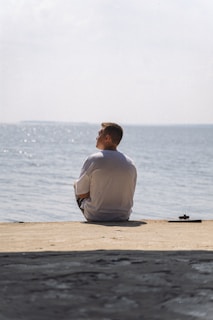 A man sitting on the beach looking at the water
