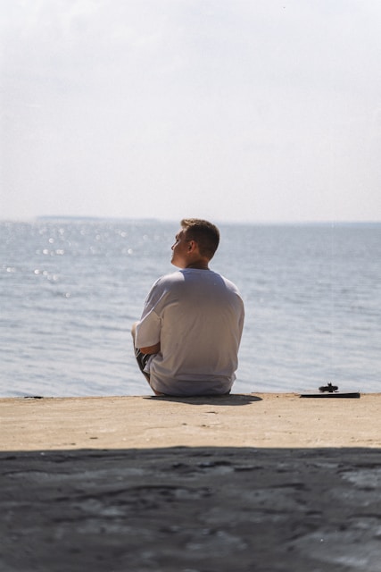 A man sitting on the beach looking at the water