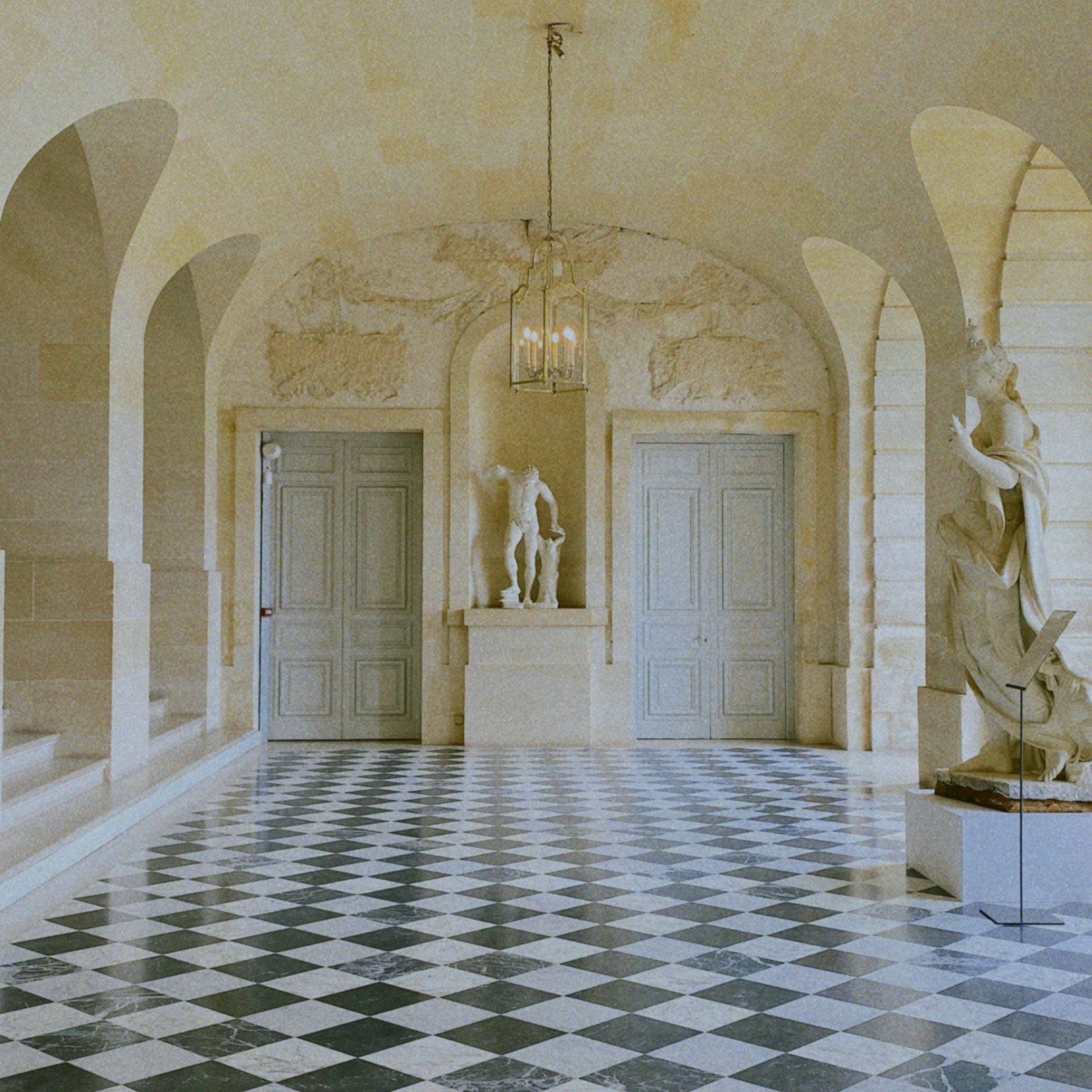 A room with a checkered floor and statues