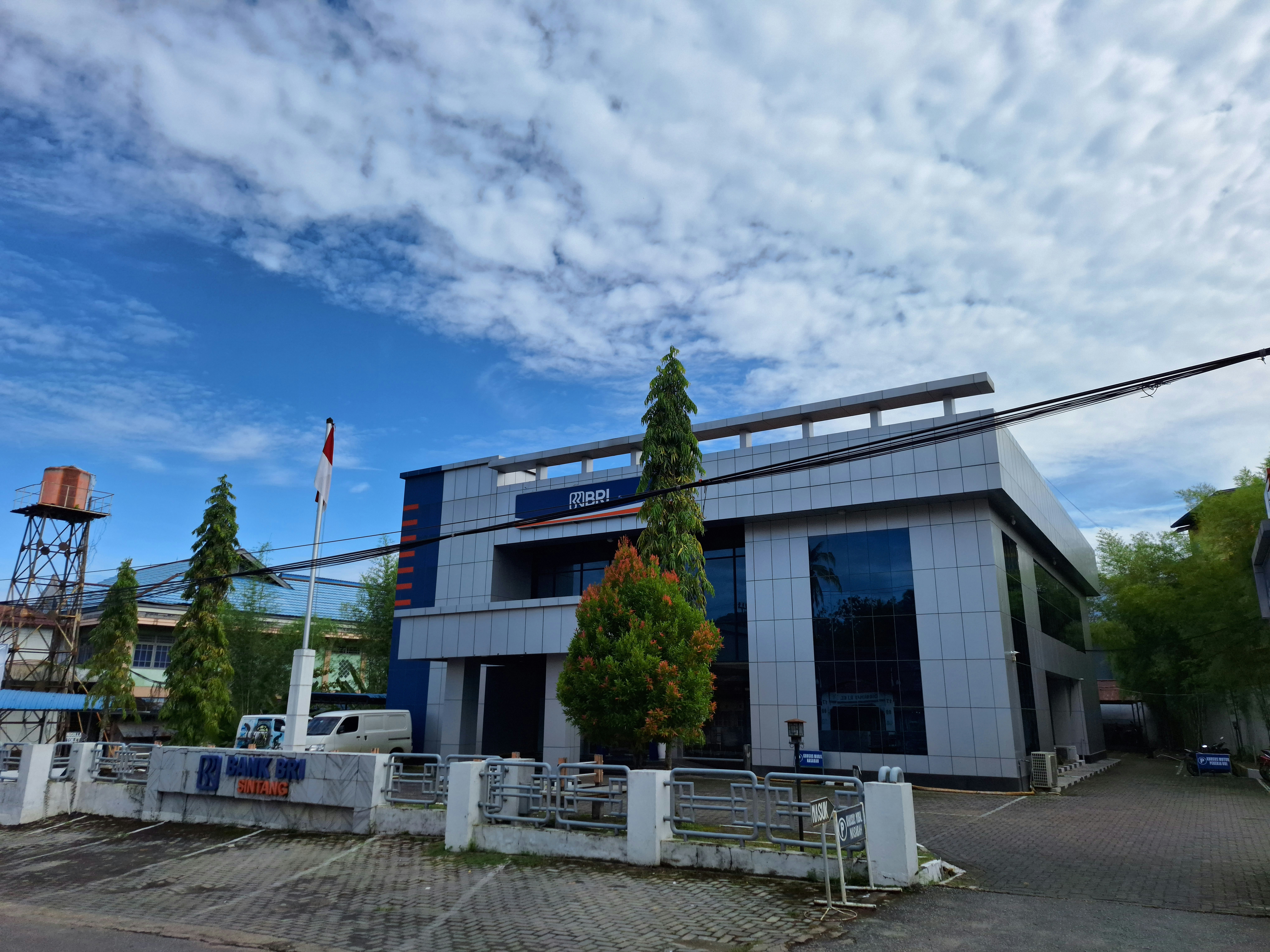 Gedung kantor pusat Bank Mandiri yang megah di Jakarta dengan arsitektur modern dan langit biru cerah