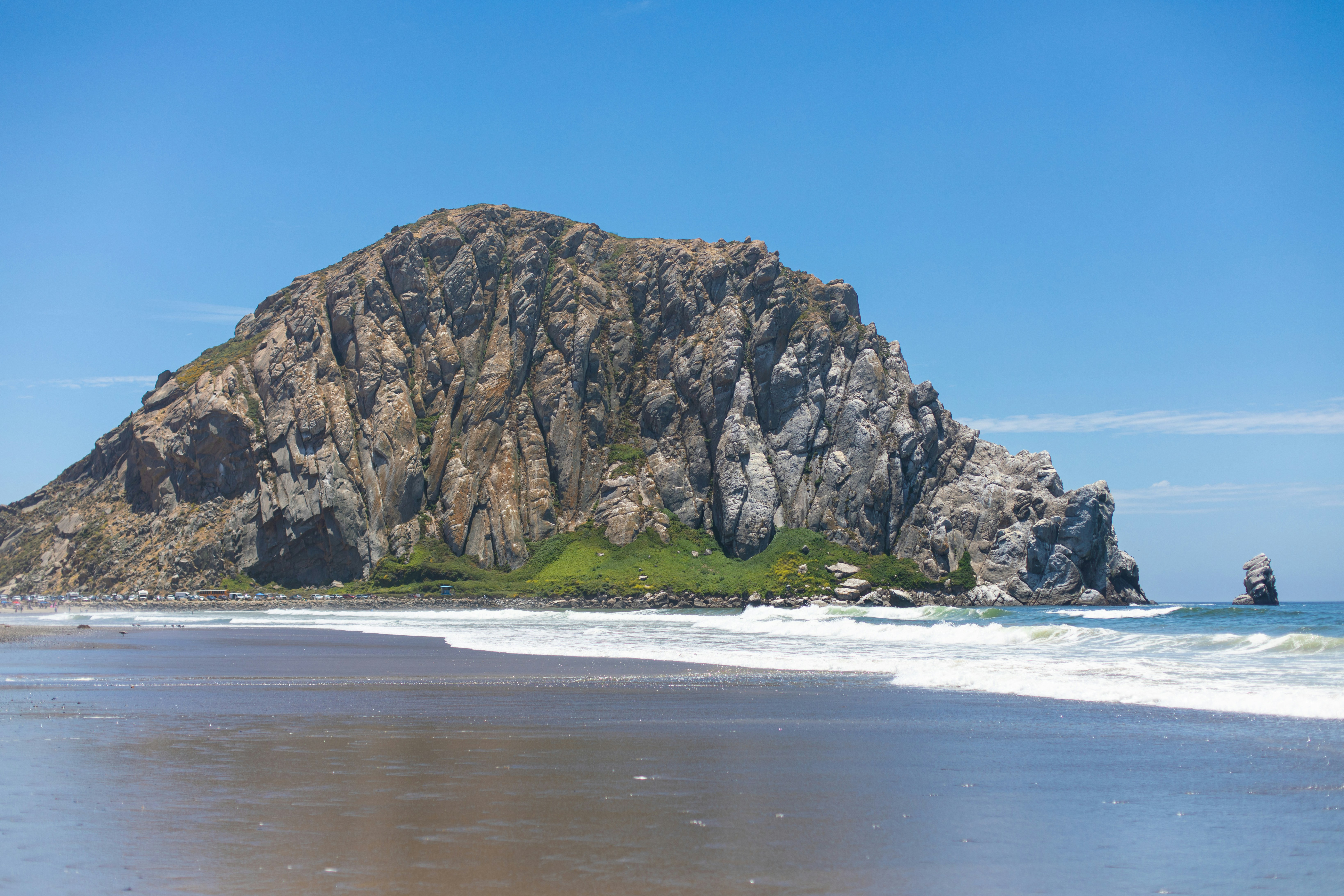 A large rock sitting on top of a beach next to the ocean