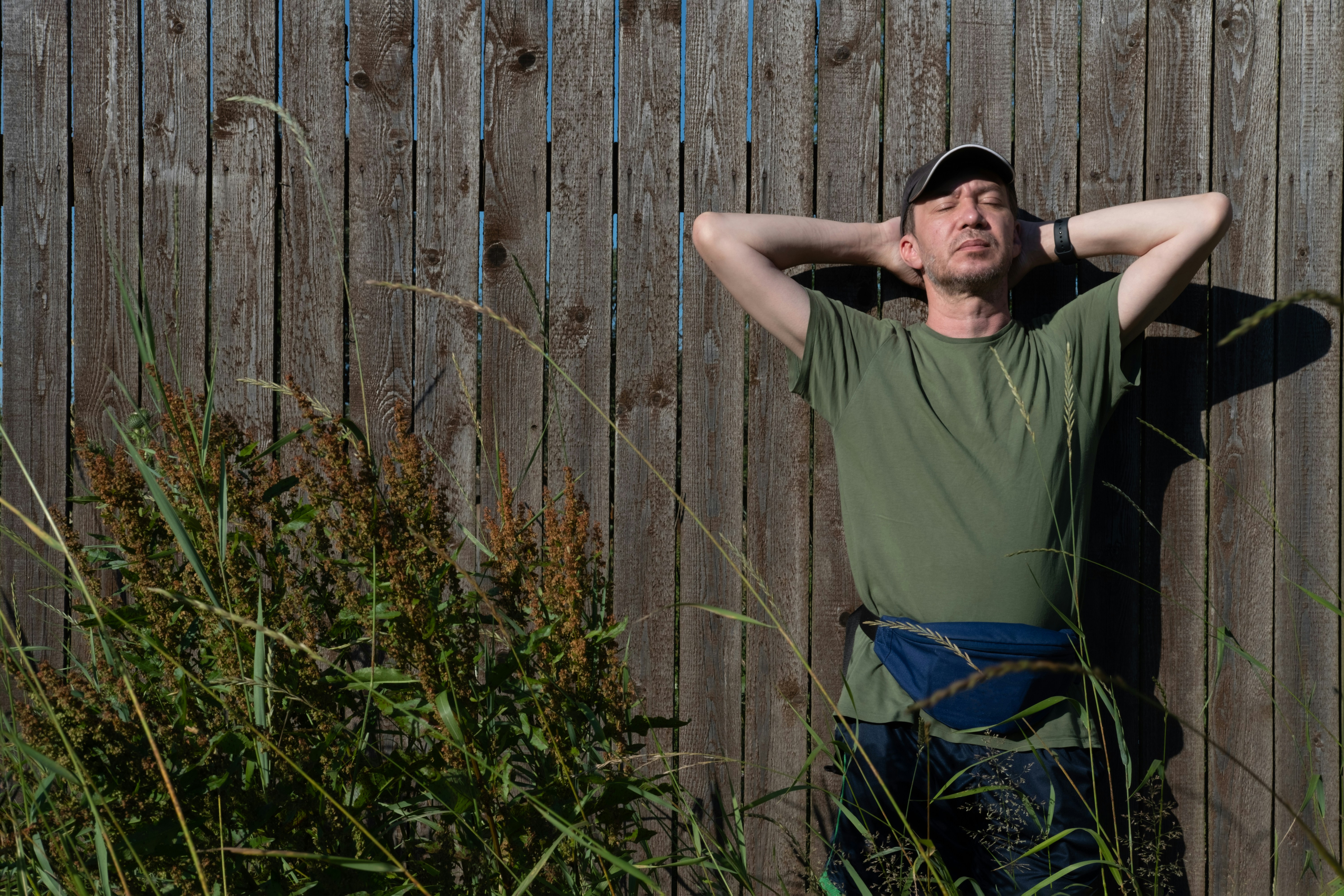 A man standing in front of a wooden fence