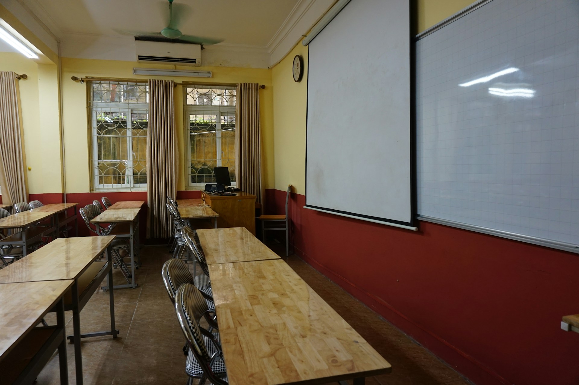 A classroom with tables and chairs and a whiteboard