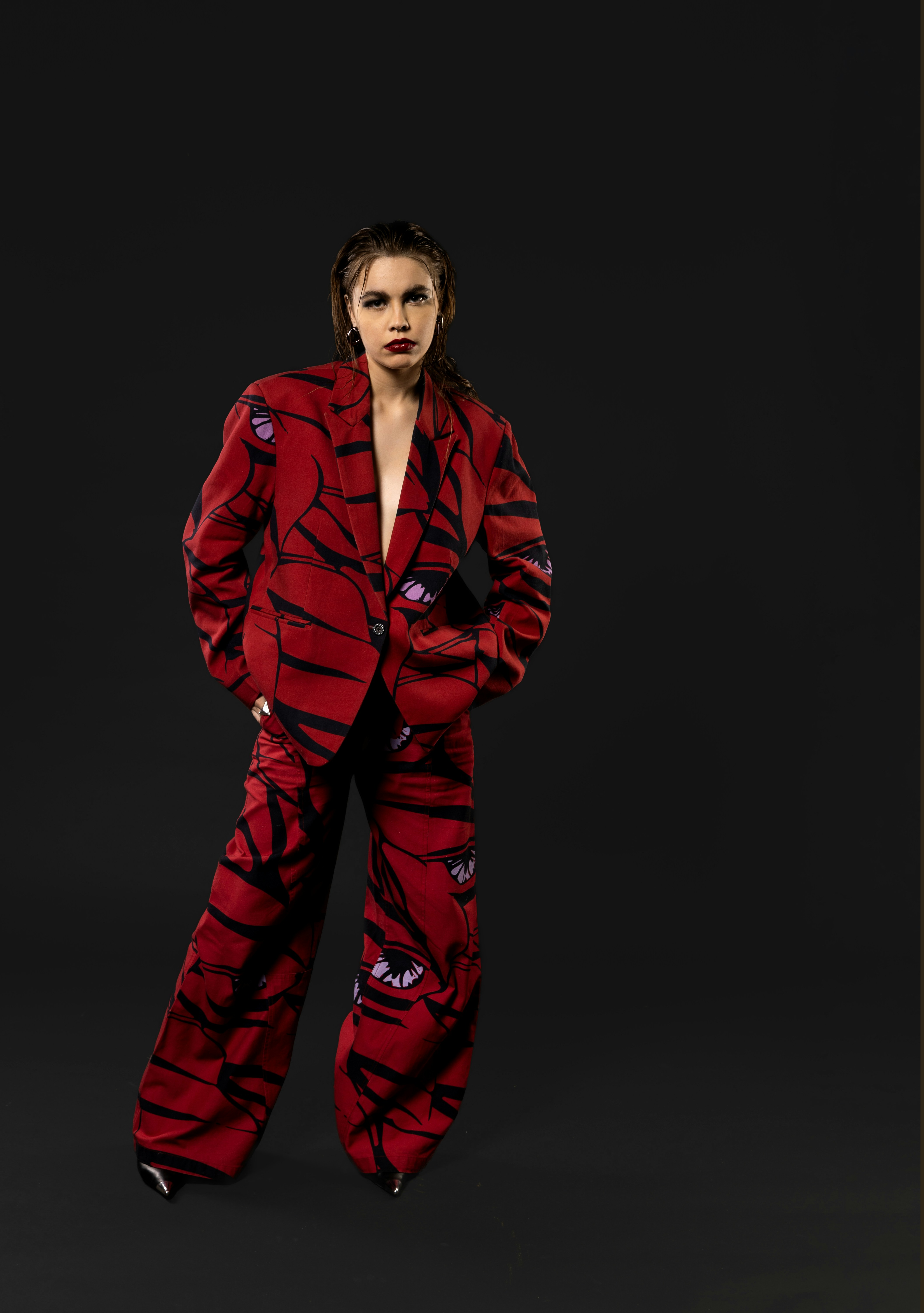 A woman in a red suit standing in front of a black background photo ...