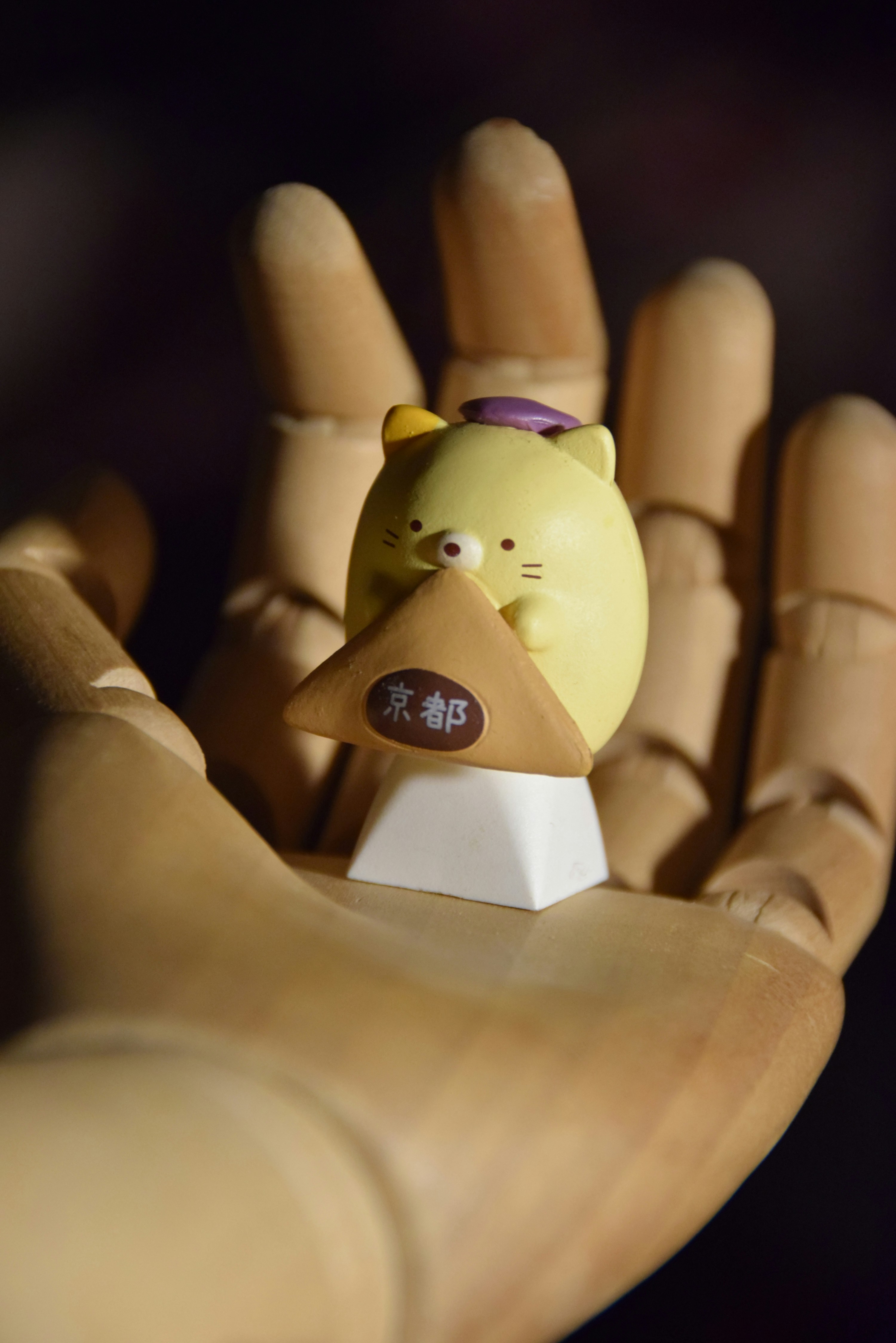 A yellow bird figurine sitting on top of a hand