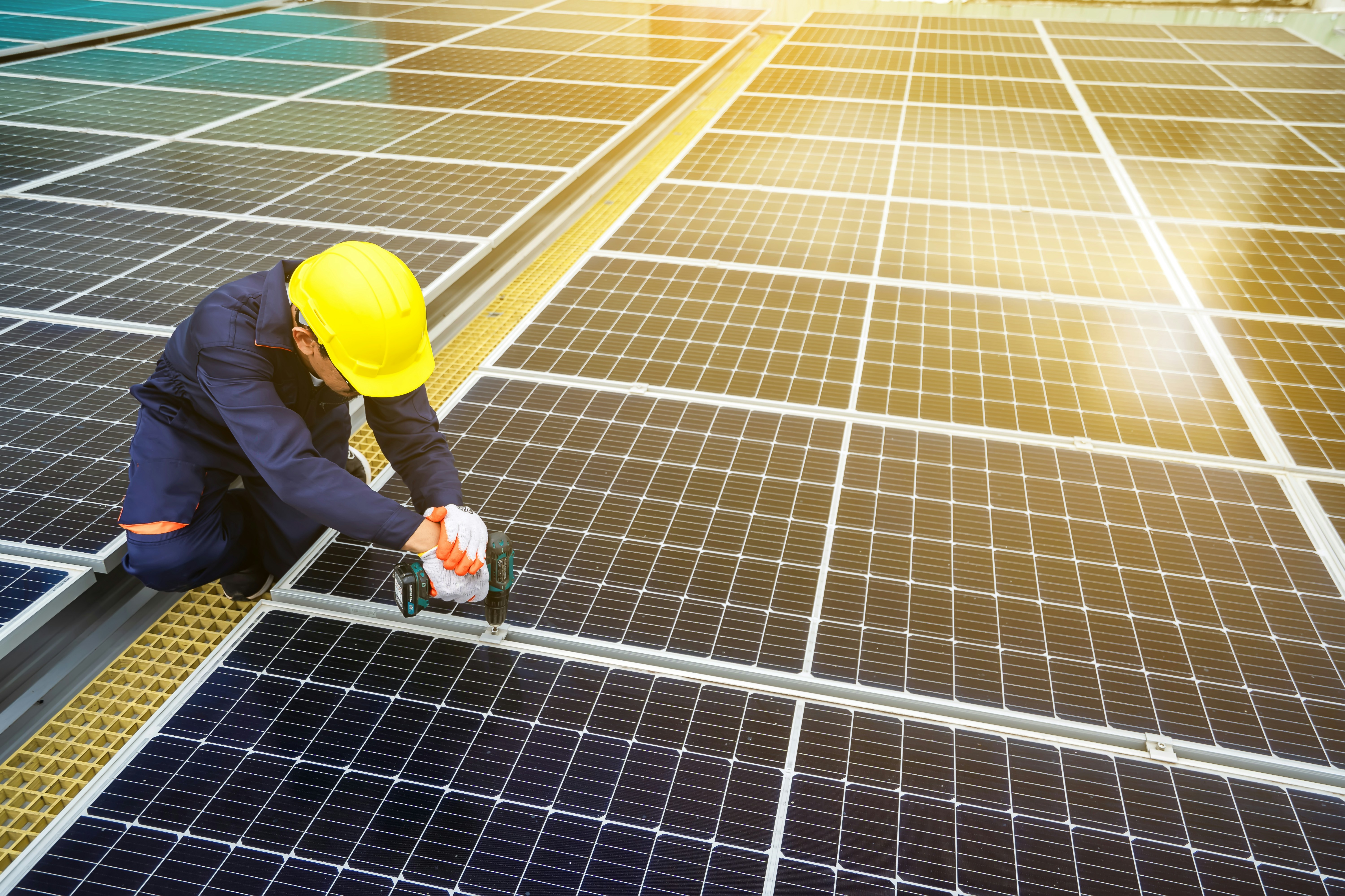Un hombre con un casco trabajando en un panel solar