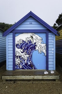 A blue building with a painting of a wave on it