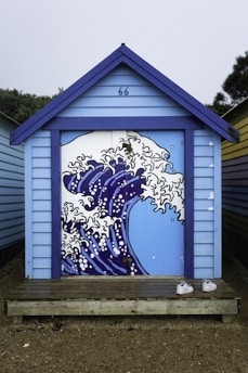 A blue building with a painting of a wave on it