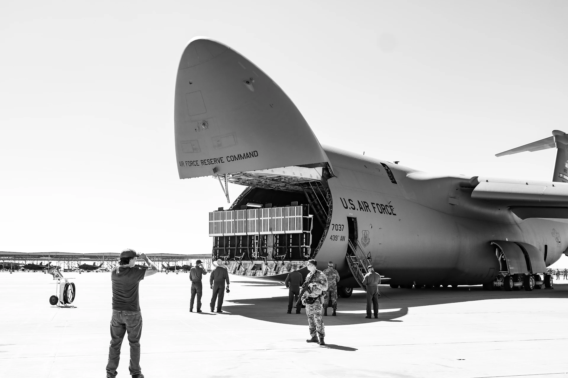 A black and white photo of people standing in front of an airplane