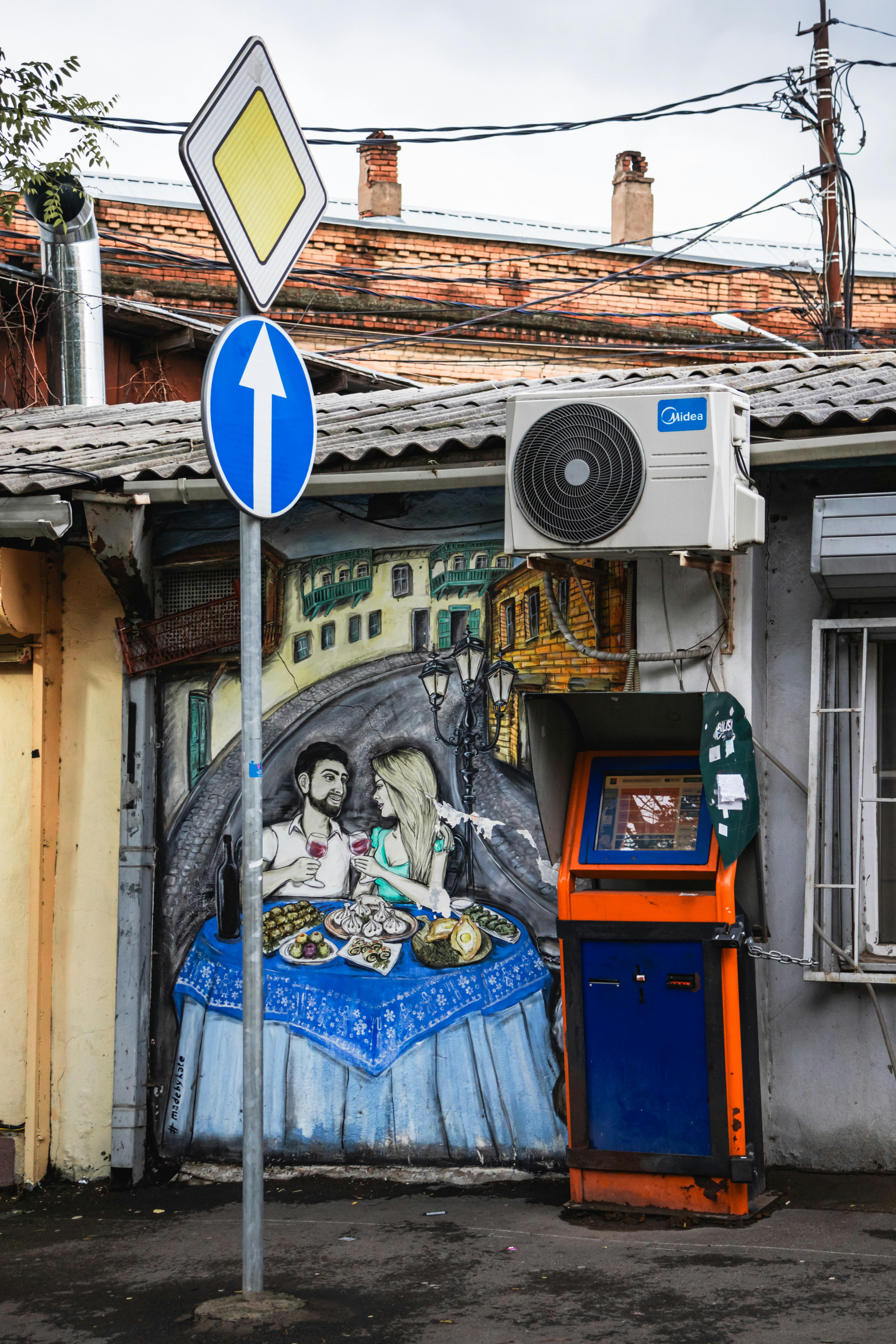 A street sign next to a building with a mural on it