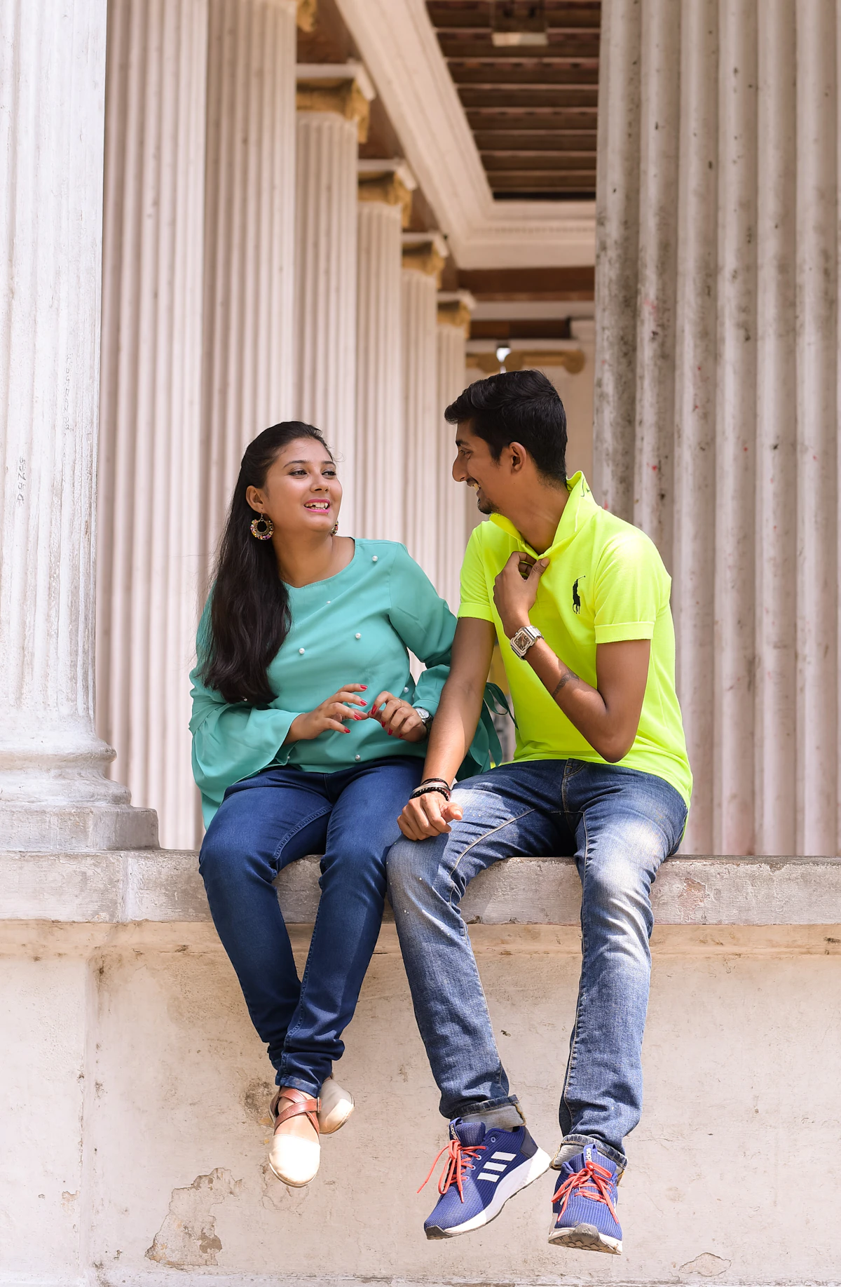 South Asian man and woman sitting together on stone steps having an animated, cheerful conversation outdoors