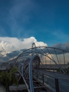 A roller coaster going over a bridge on a cloudy day