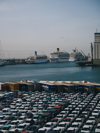 A parking lot filled with lots of cars next to a large cruise ship