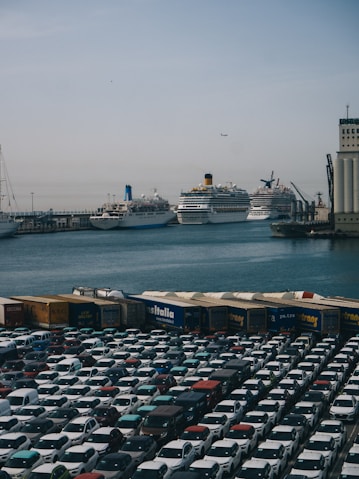 A parking lot filled with lots of cars next to a large cruise ship