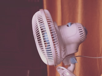 A white fan sitting on top of a window sill