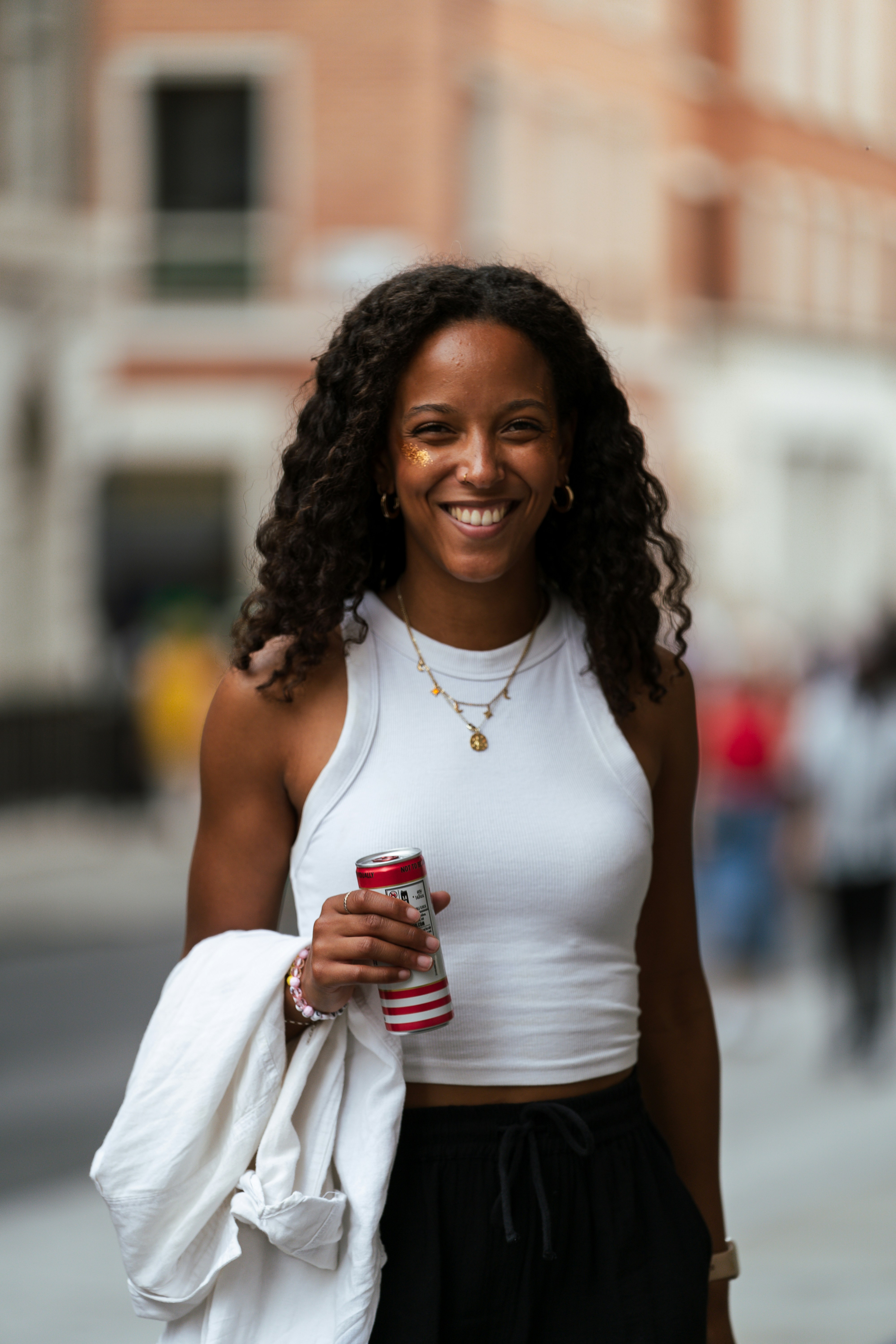 A woman is smiling while holding a drink