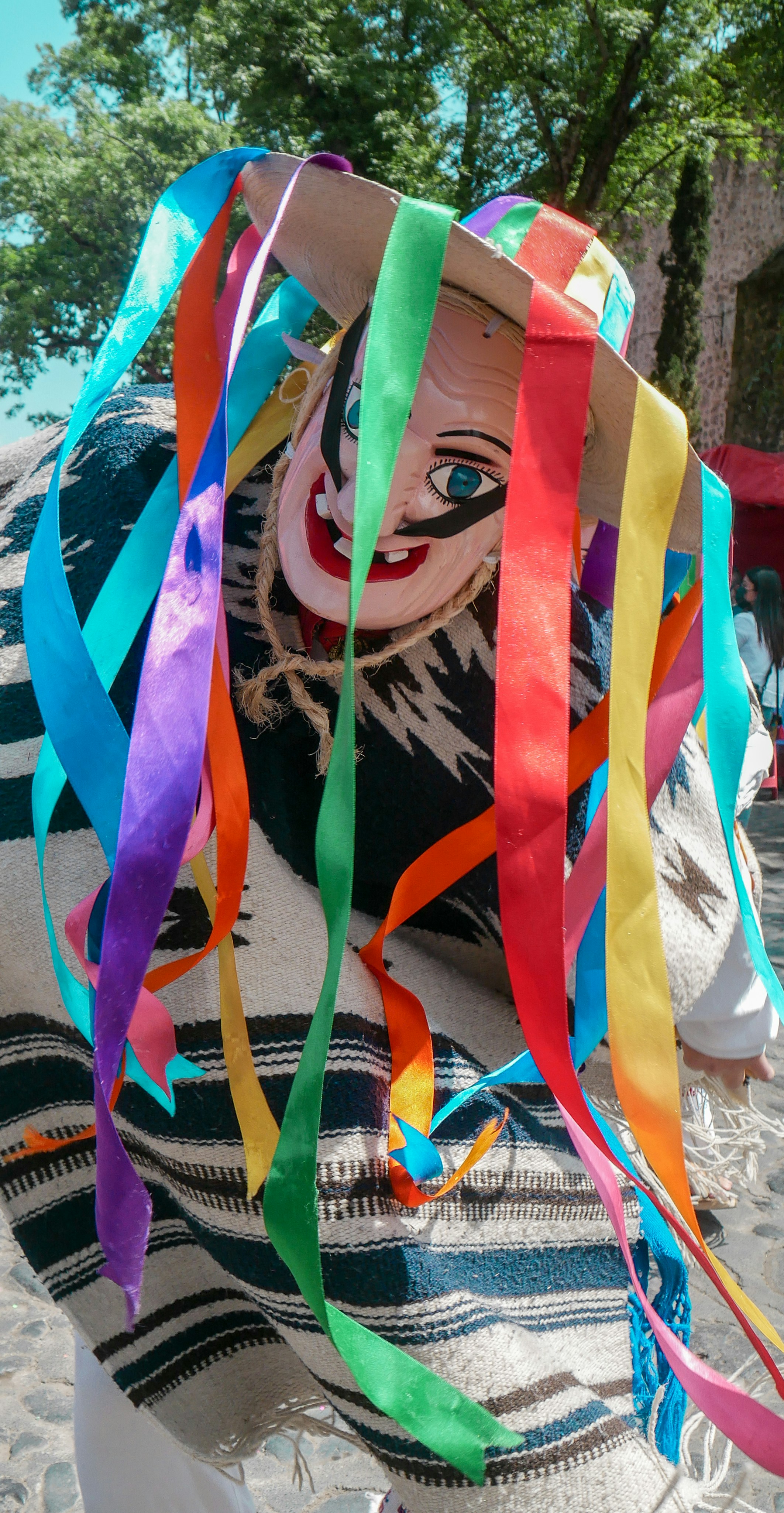 A person wearing a clown mask and colorful streamers