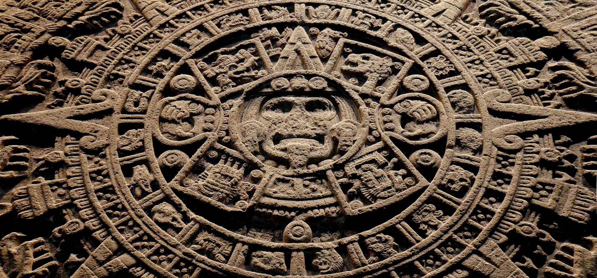 A stone carving of a face with many symbols on it