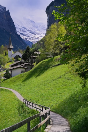 A path leading to a village with a mountain in the background