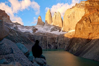 A man sitting on a rock looking at the mountains