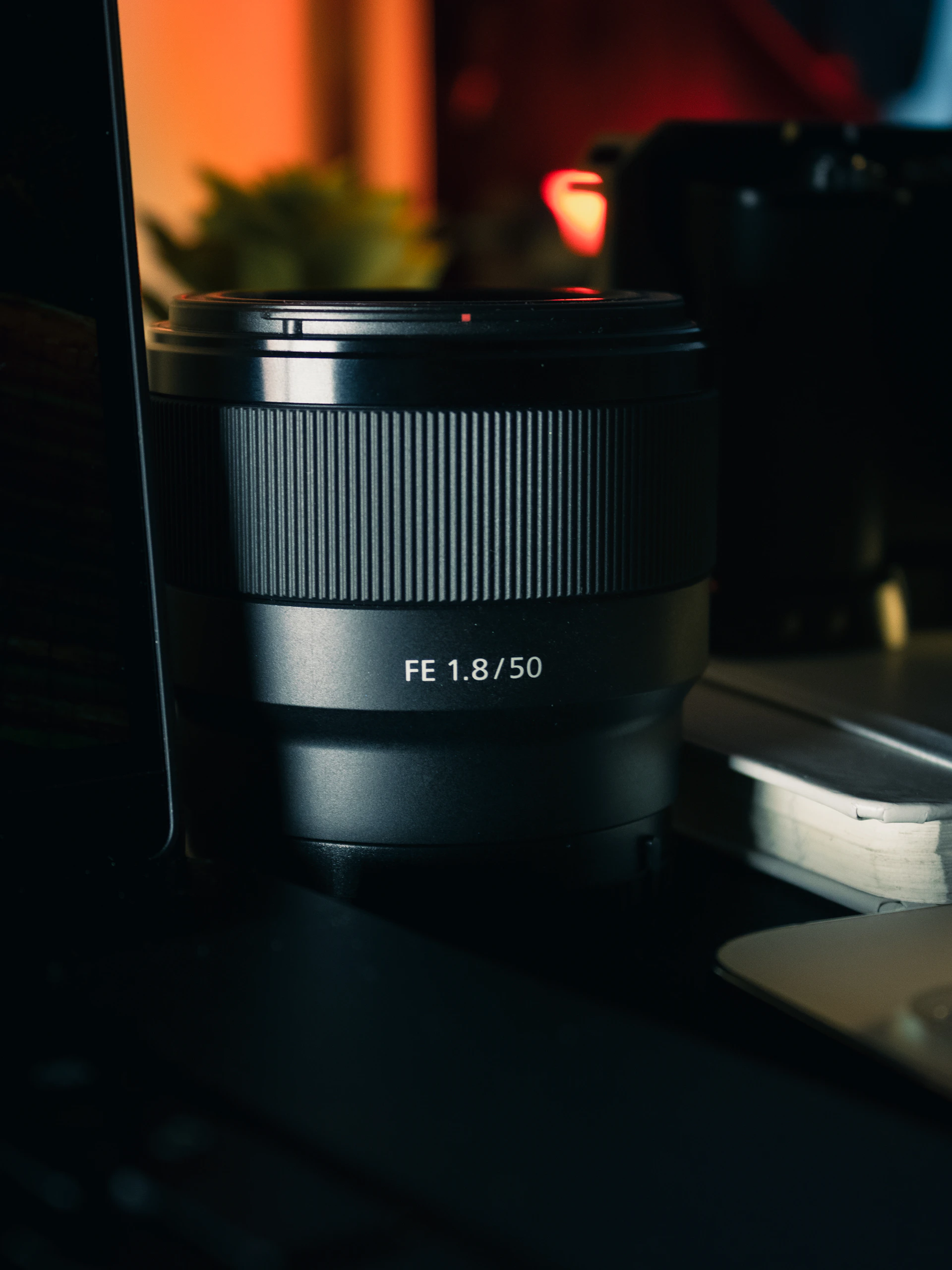 A camera lens sitting on top of a desk next to a laptop