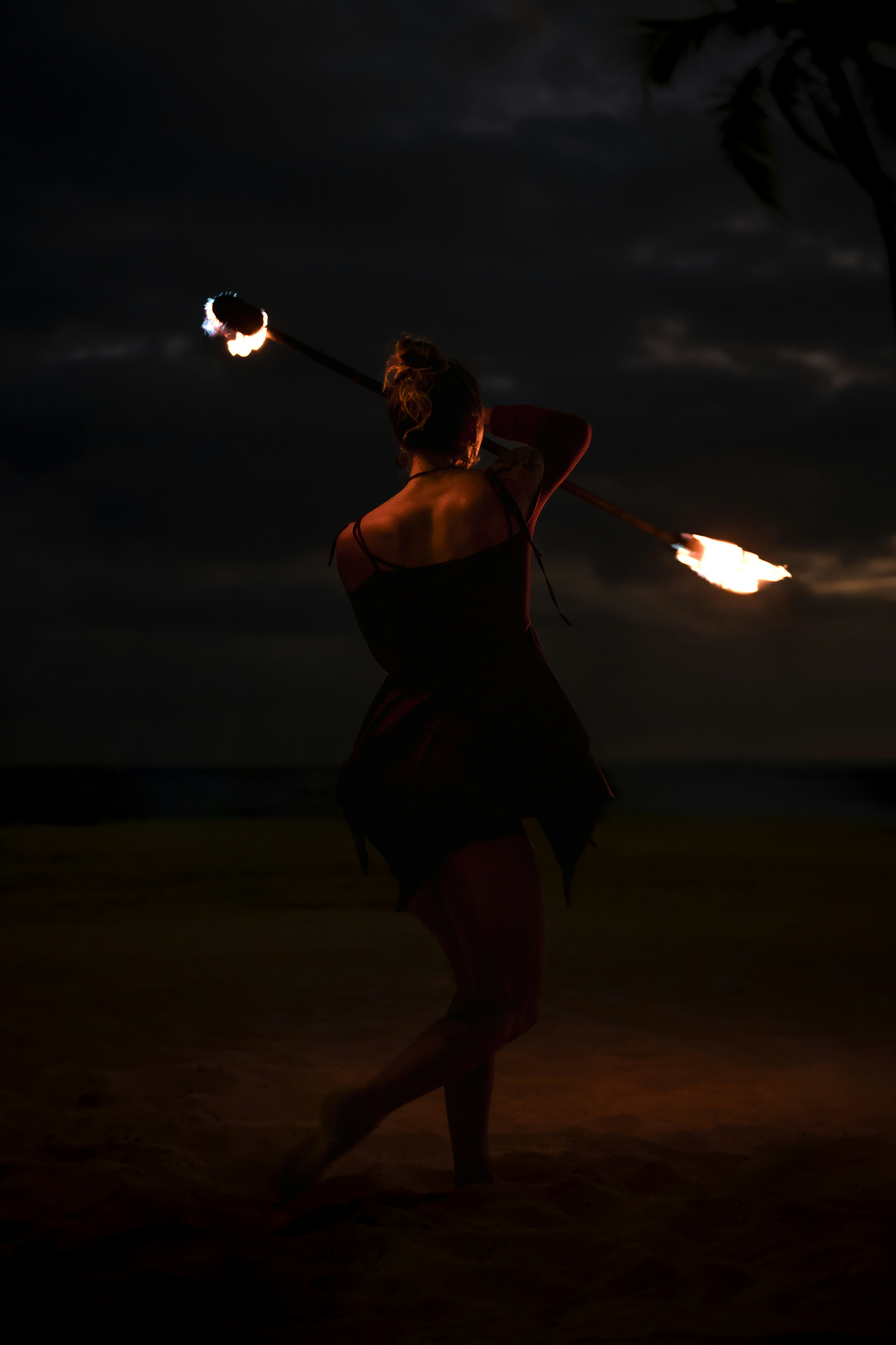 A woman in a dark dress holding a fire stick