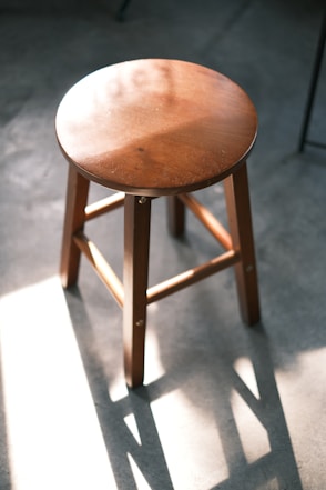 A wooden stool sitting on top of a cement floor