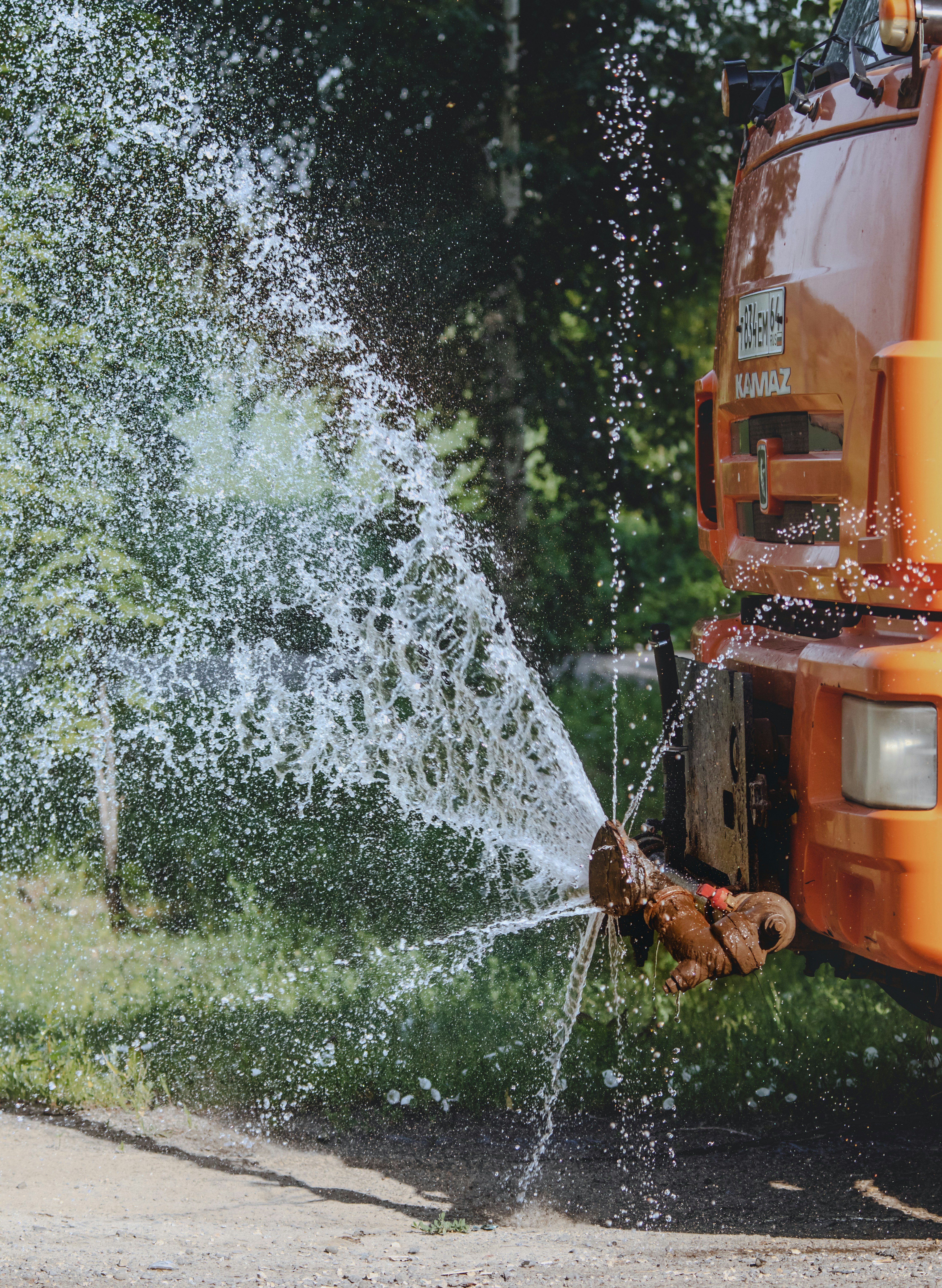 An orange truck spewing water onto the street