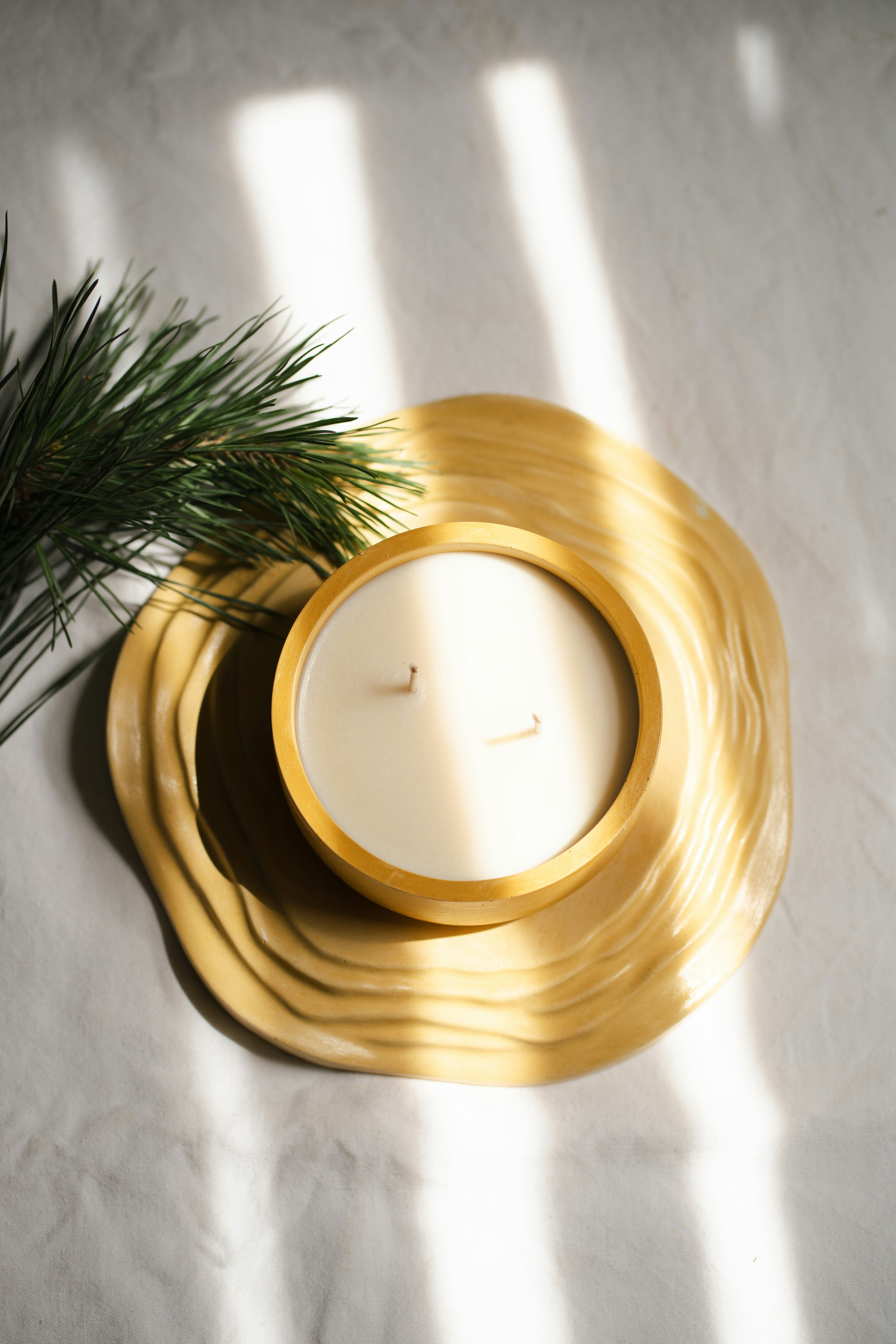 A candle sitting on top of a table next to a pine tree