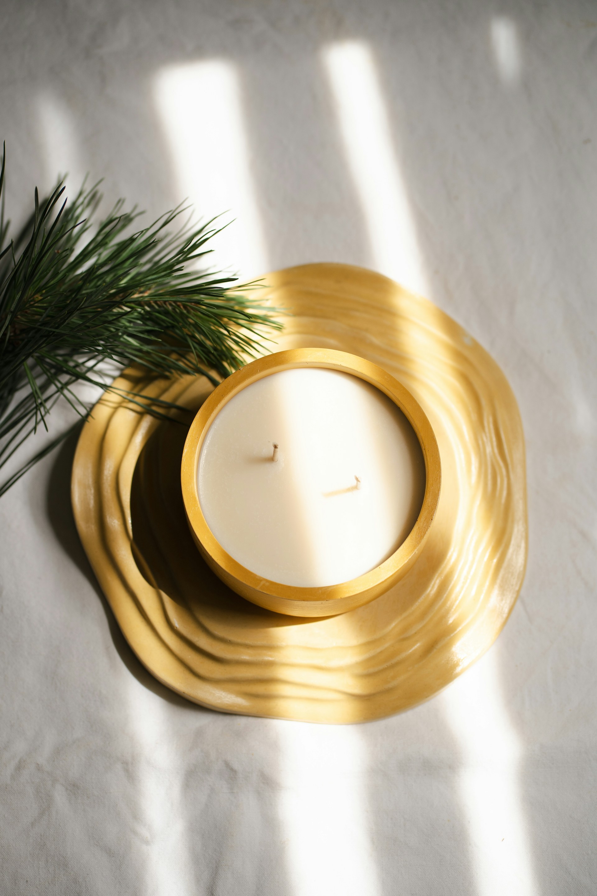 A candle sitting on top of a table next to a pine tree