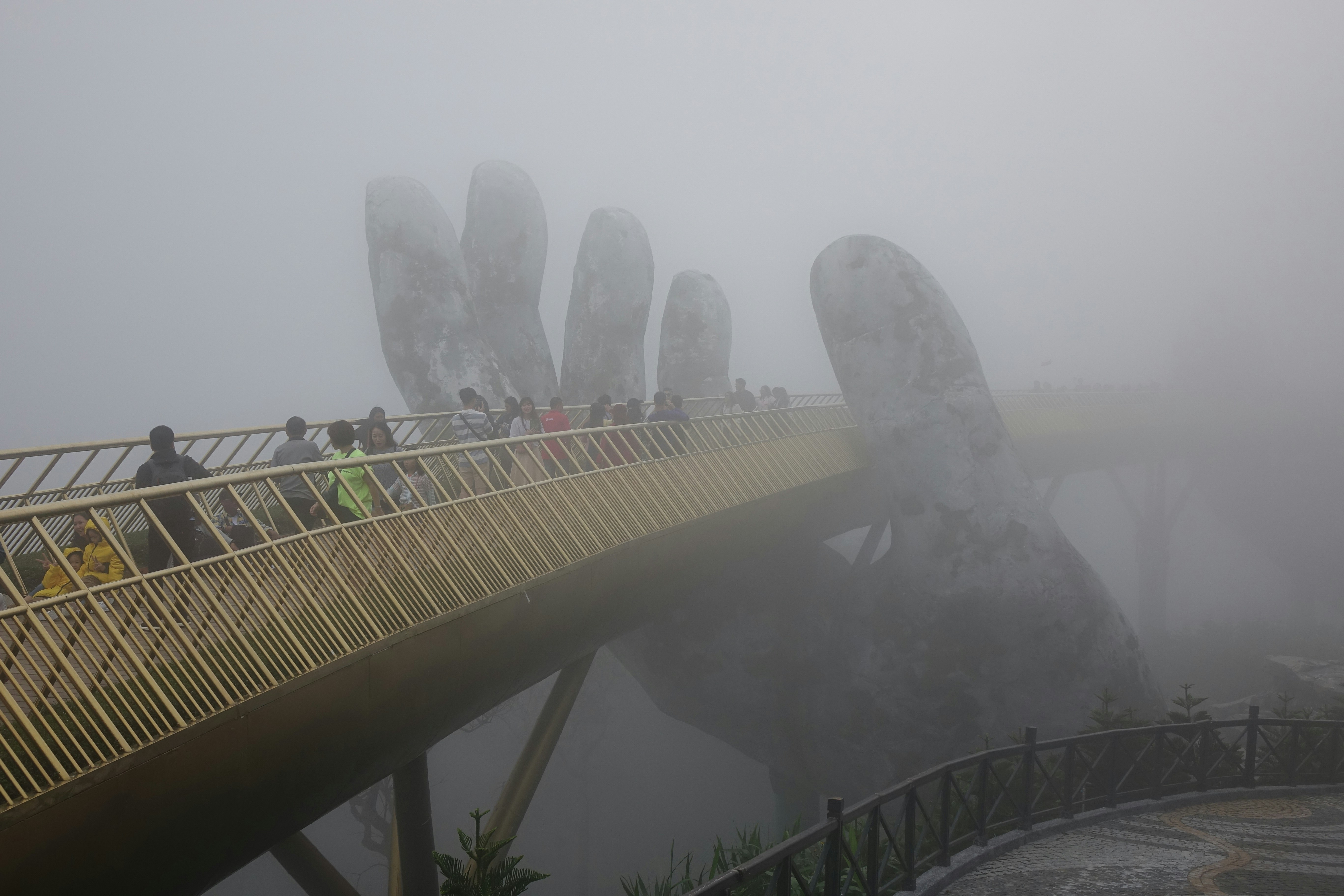 Des gens traversent un pont par temps brumeux