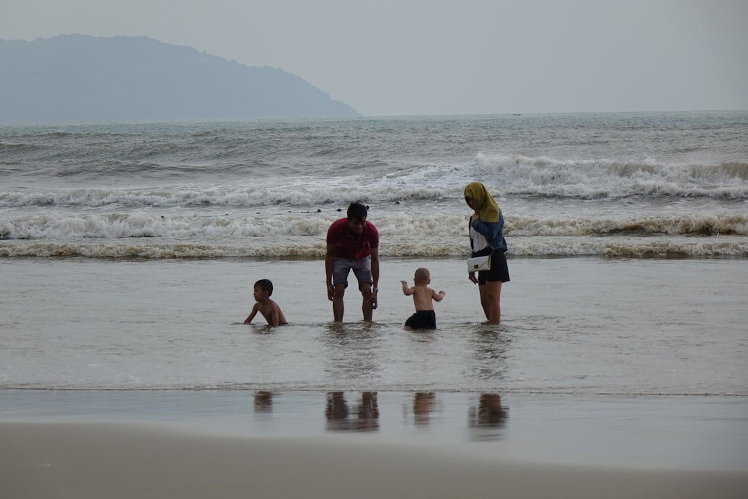 A group of people standing on top of a beach next to the ocean,