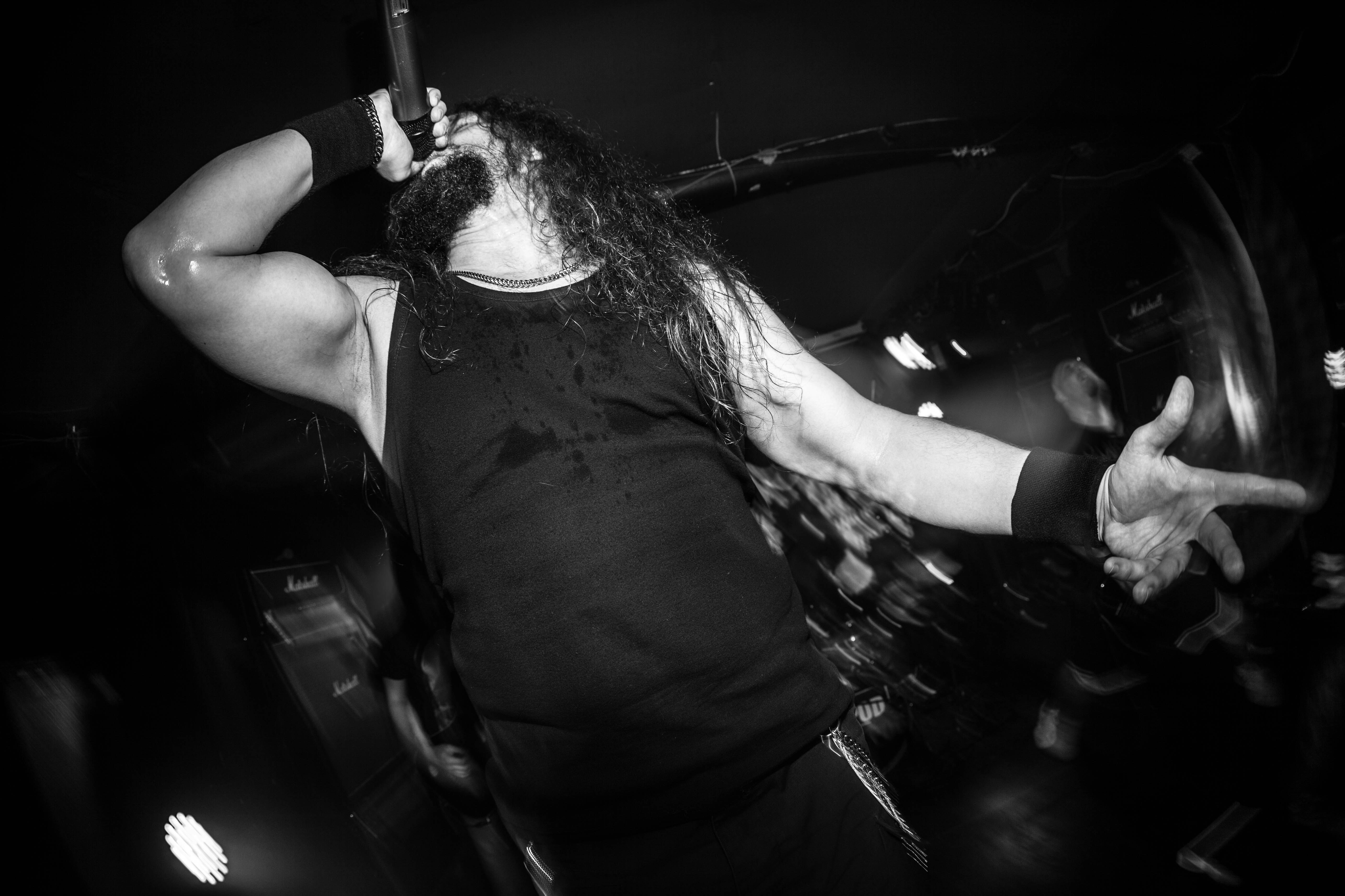 A man with long hair standing in front of a microphone