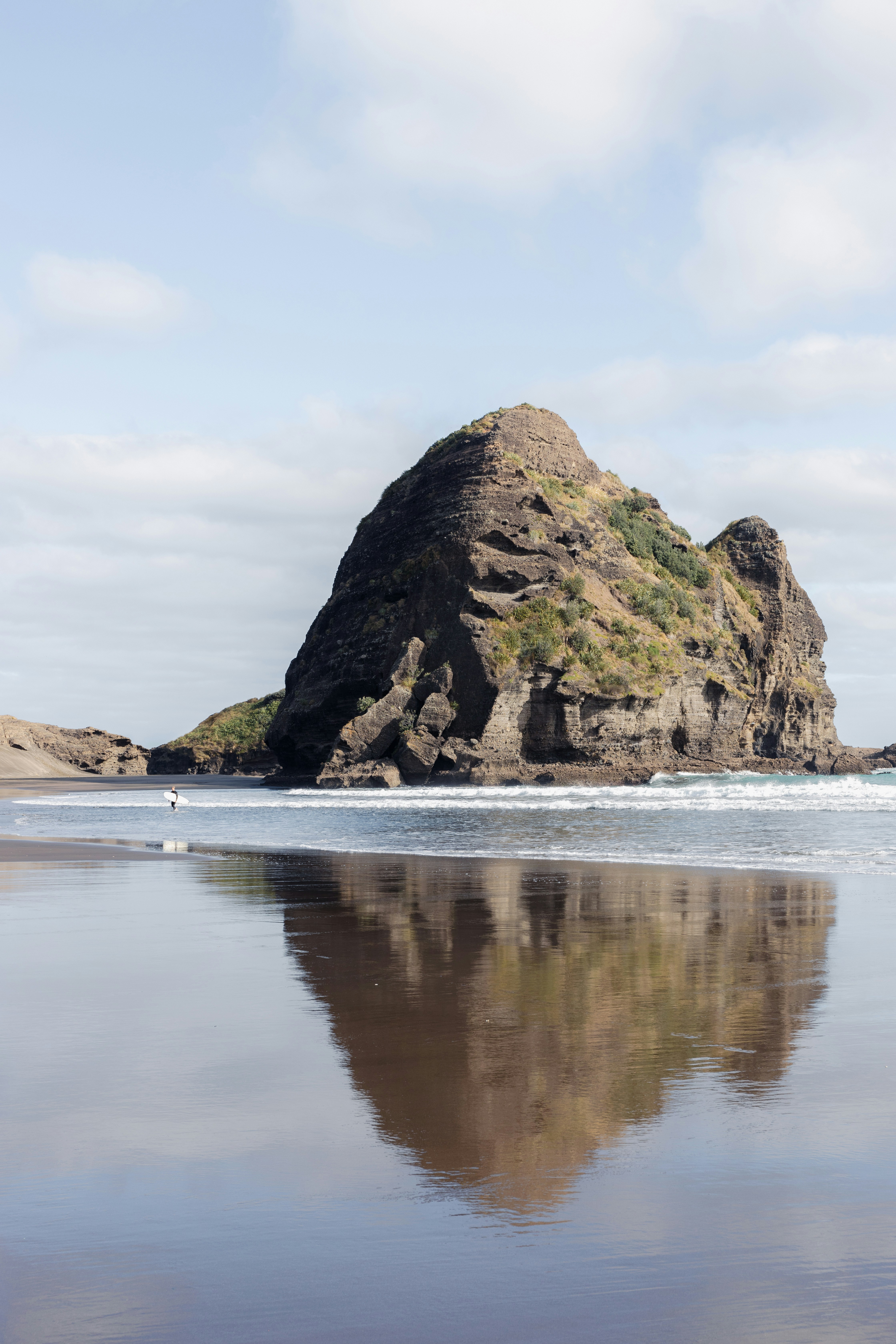 A large rock sitting on top of a beach next to the ocean