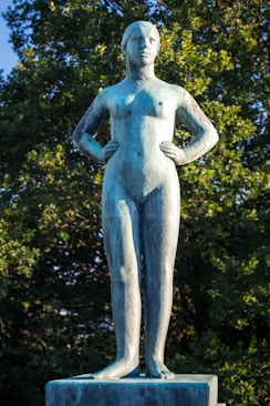A statue of a woman standing in front of trees