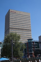 A group of people walking in front of a tall building